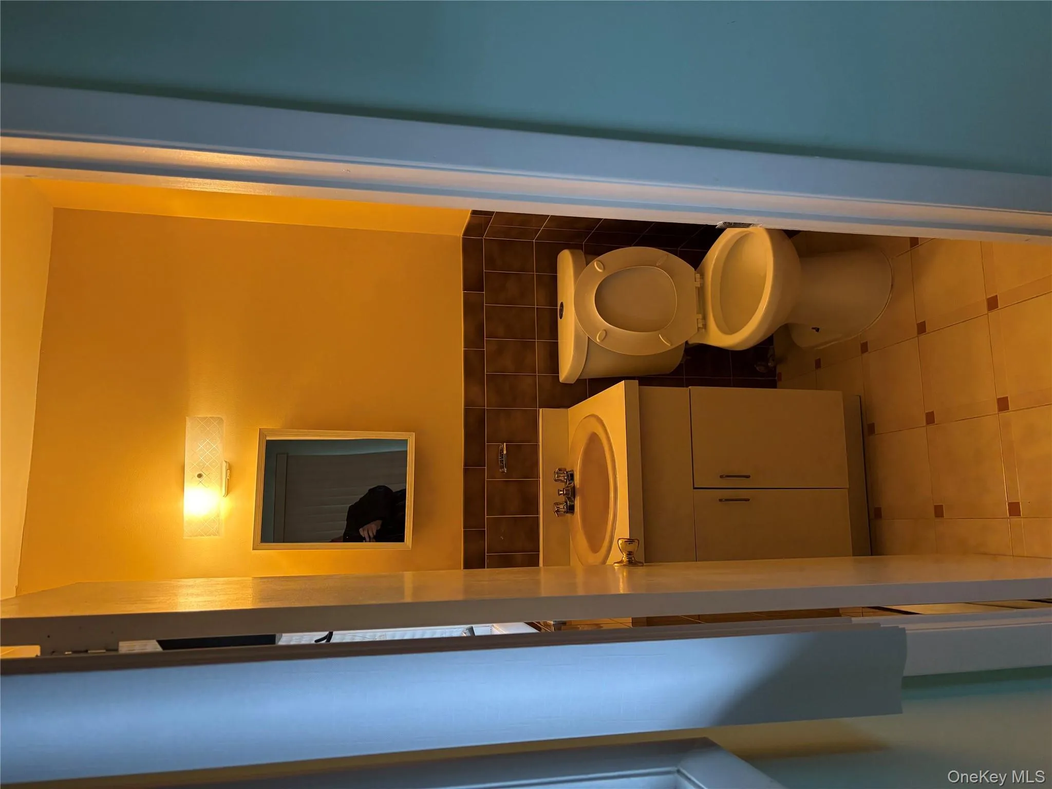 Half bathroom featuring vanity, tile walls, light tile patterned flooring, and a wainscoted wall Half bathroom featuring vanity, tile walls, light tile patterned flooring, and a wainscoted wall