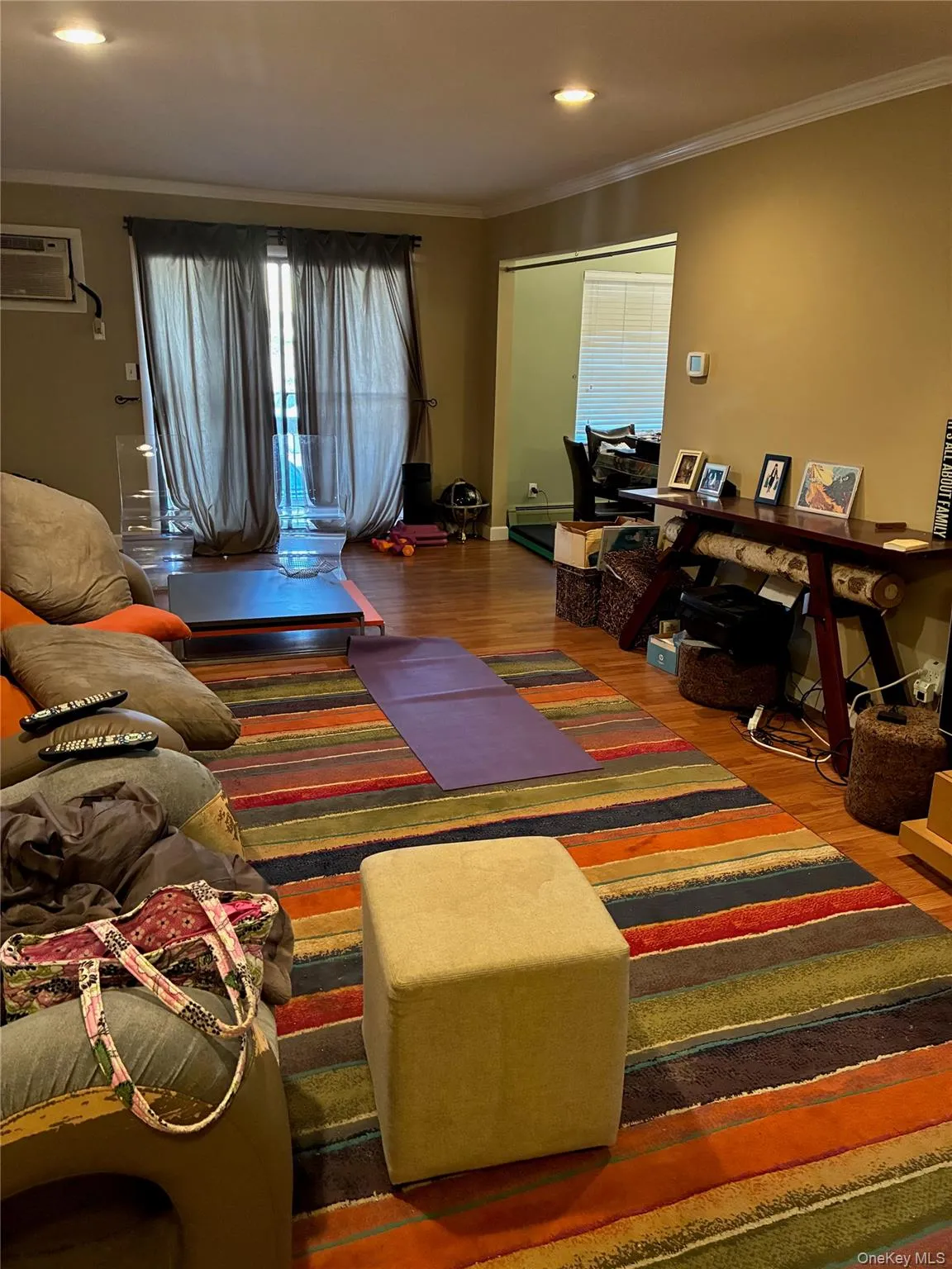 Living area with ornamental molding, wood finished floors, and a wall mounted new air conditioner. Deck off living room Living area with ornamental molding, wood finished floors, and a wall mounted new air conditioner. Deck off living room