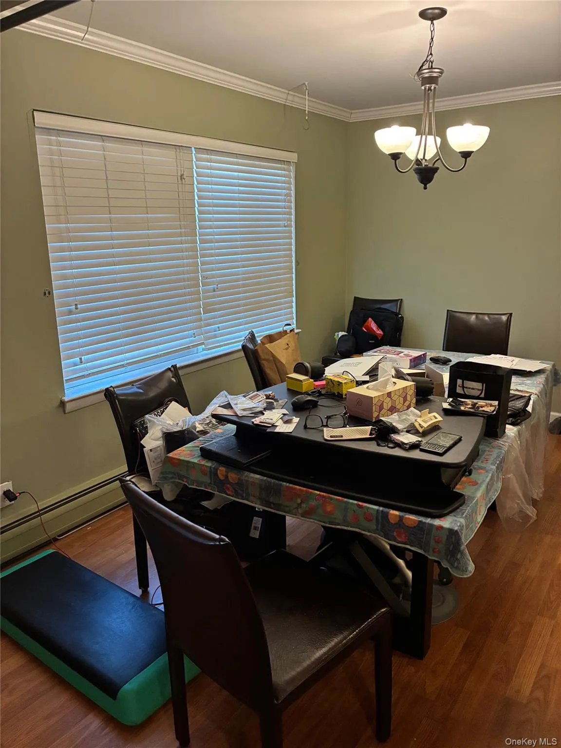 Dining space featuring a baseboard radiator, wood finished floors, crown molding, and a chandelier Dining space featuring a baseboard radiator, wood finished floors, crown molding, and a chandelier