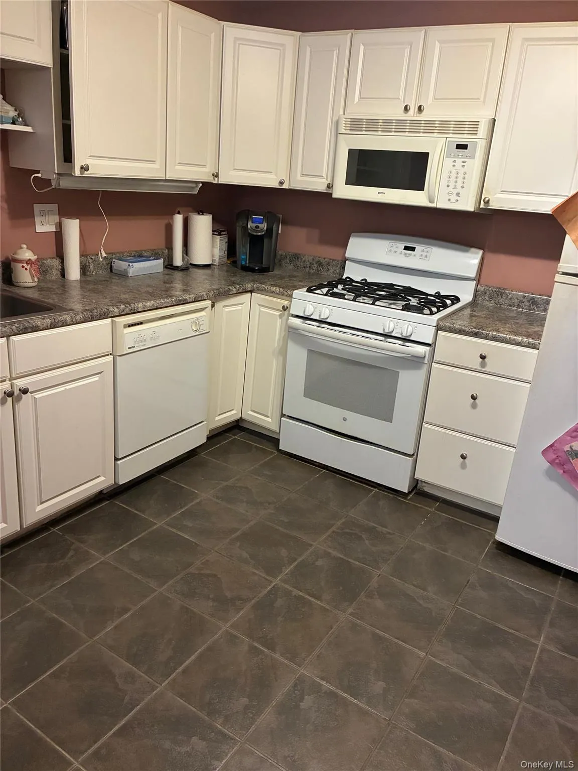 Kitchen with white appliances, white, cabinetry, and dark countertops Kitchen with white appliances, white, cabinetry, and dark countertops