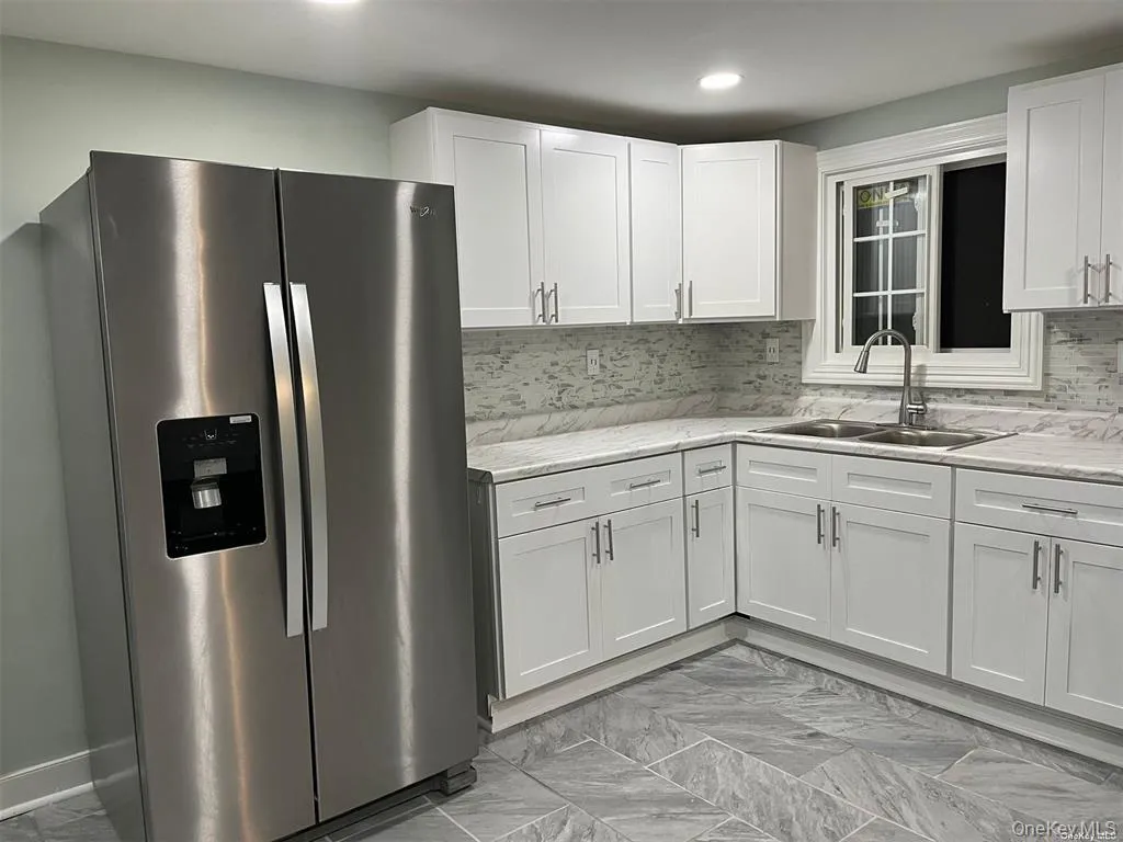 Kitchen with stainless steel fridge, light marble finish flooring, white cabinets, decorative backsplash, and recessed lighting Kitchen with stainless steel fridge, light marble finish flooring, white cabinets, decorative backsplash, and recessed lighting