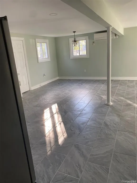 Basement featuring freestanding refrigerator and a wall mounted AC Basement featuring freestanding refrigerator and a wall mounted AC