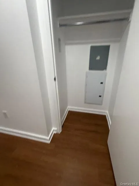 Hallway with dark wood-style flooring and electric panel Hallway with dark wood-style flooring and electric panel