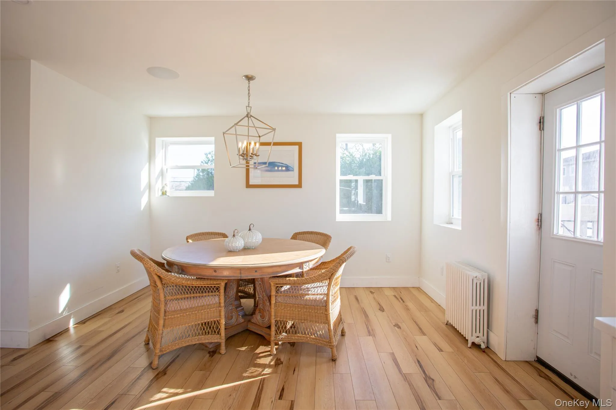 Dining space featuring radiator, light wood finished floors, and a chandelier Dining space featuring radiator, light wood finished floors, and a chandelier