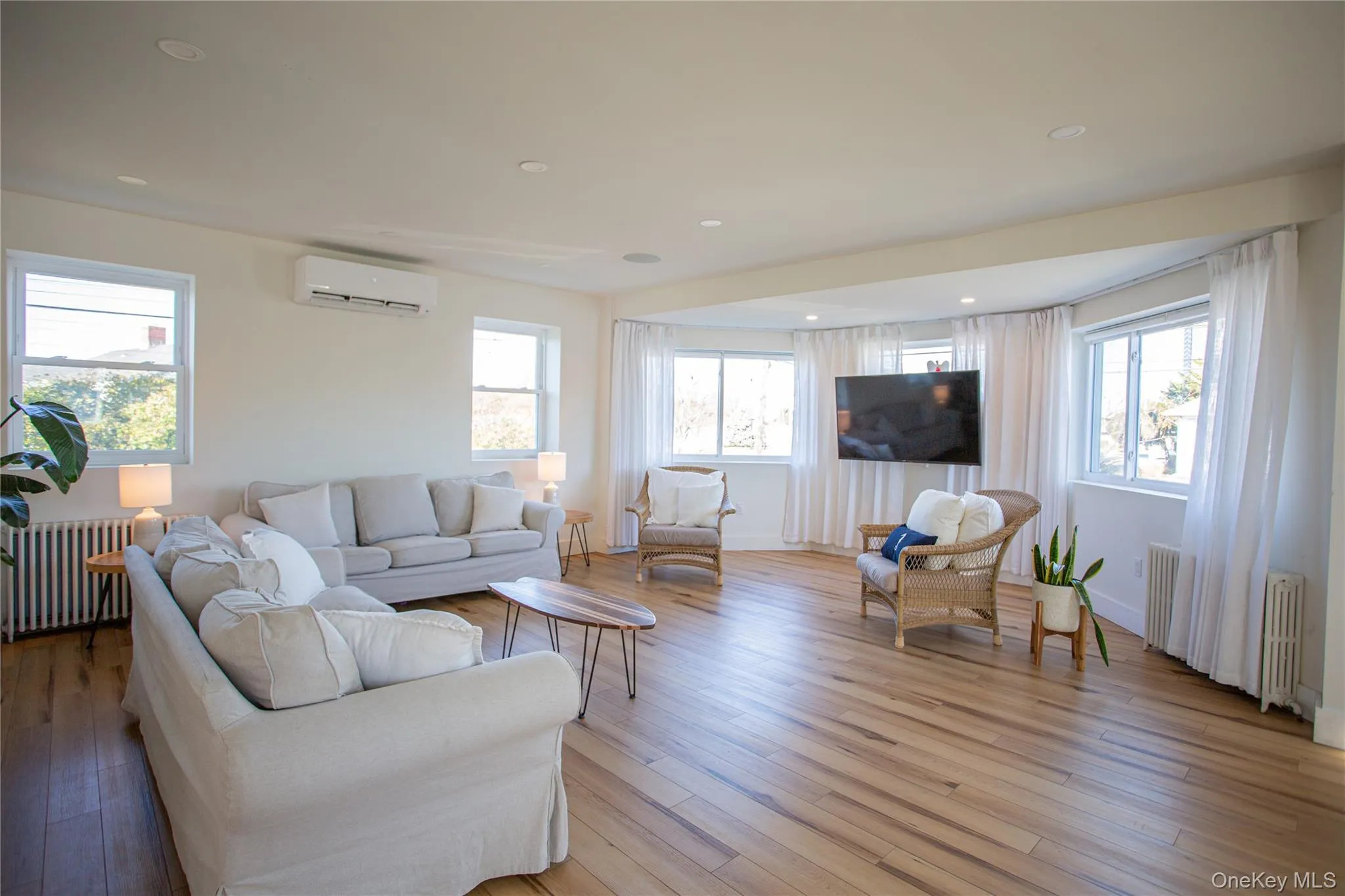 Living area featuring radiator heating unit, healthy amount of natural light, wood-type flooring, and recessed lighting Living area featuring radiator heating unit, healthy amount of natural light, wood-type flooring, and recessed lighting