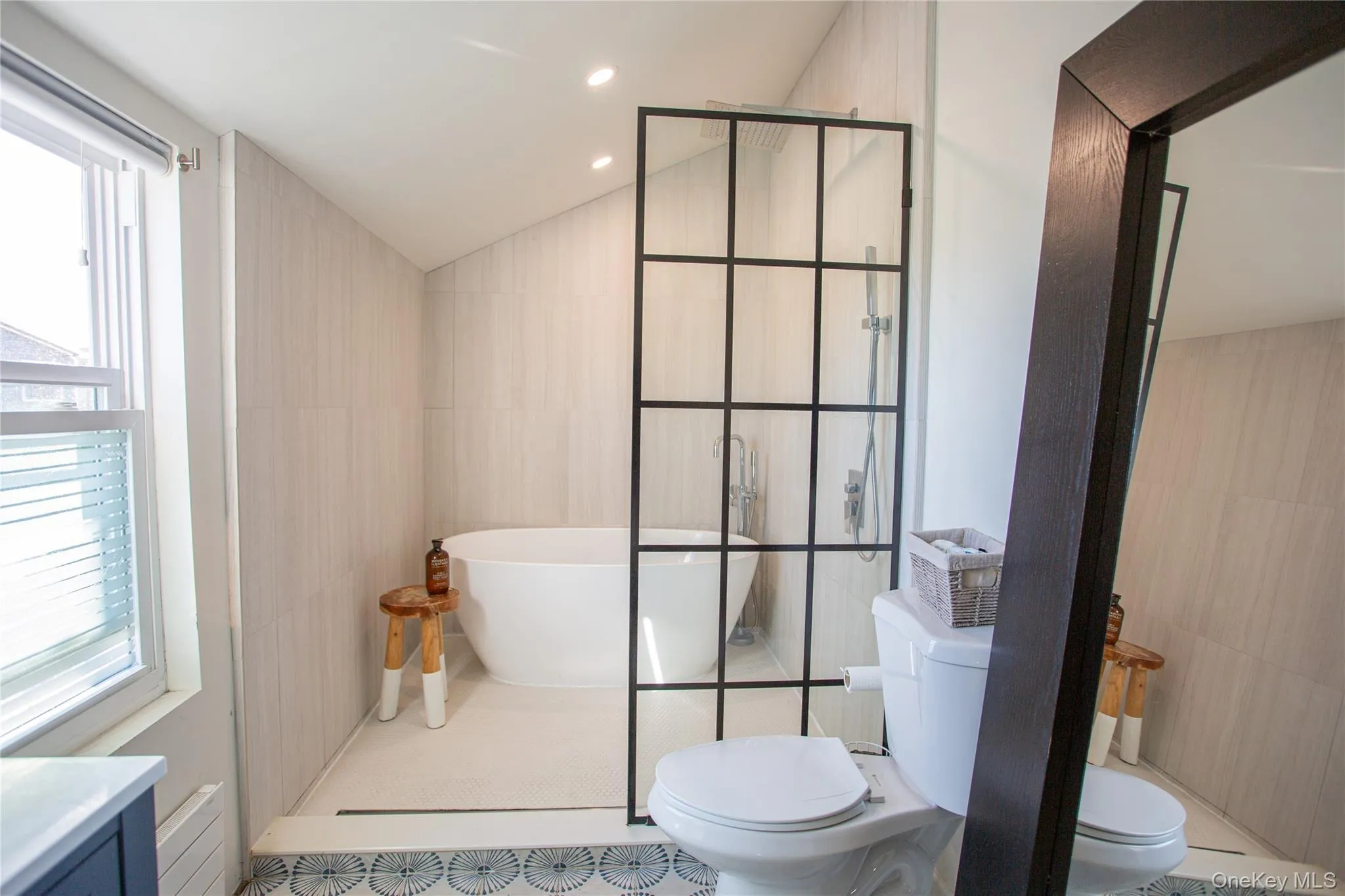 Full bathroom featuring tile walls, a freestanding tub, vaulted ceiling, a walk in shower, and recessed lighting Full bathroom featuring tile walls, a freestanding tub, vaulted ceiling, a walk in shower, and recessed lighting