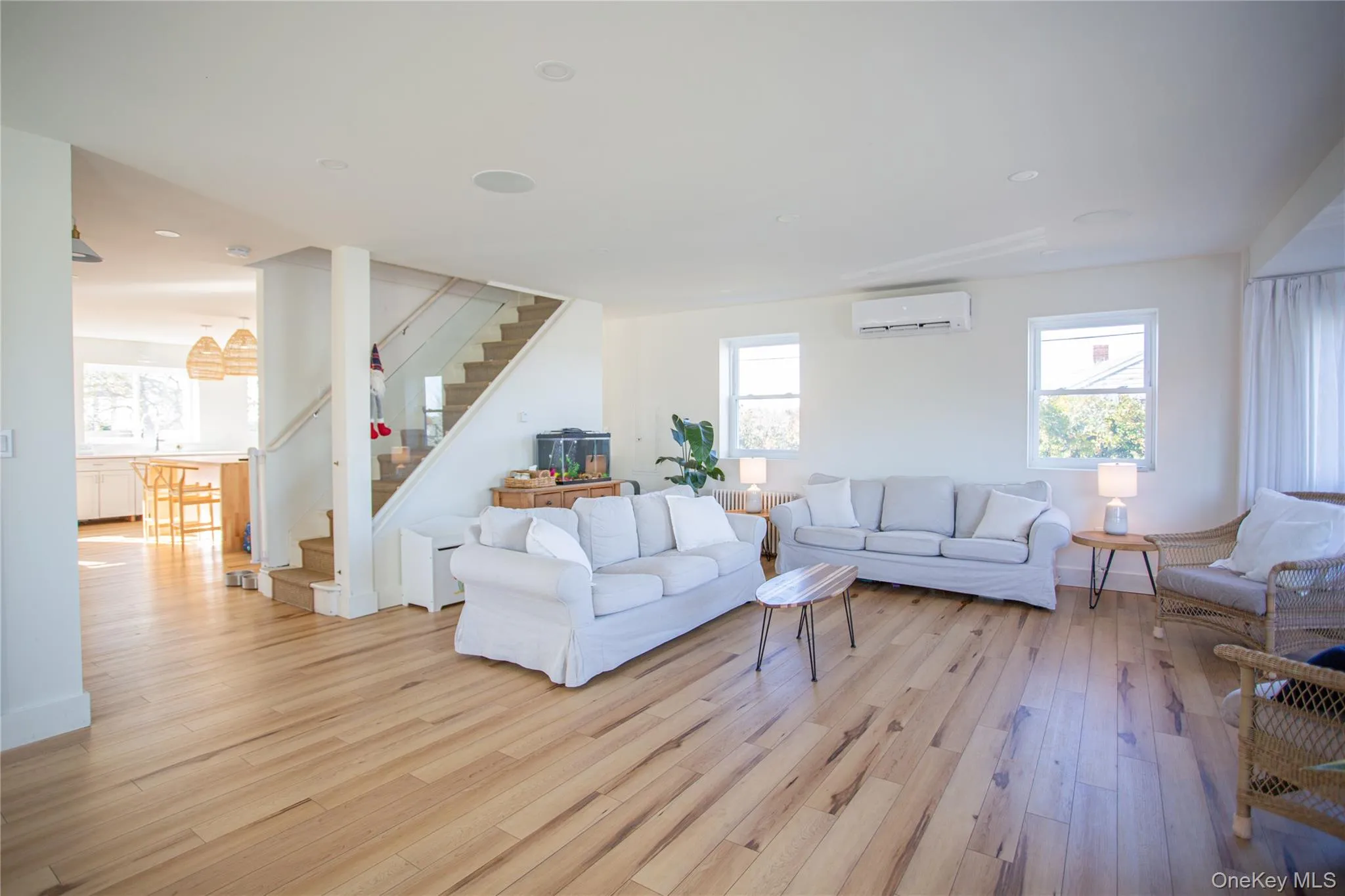 Living room with stairway, light wood-style floors, and a wall unit AC Living room with stairway, light wood-style floors, and a wall unit AC