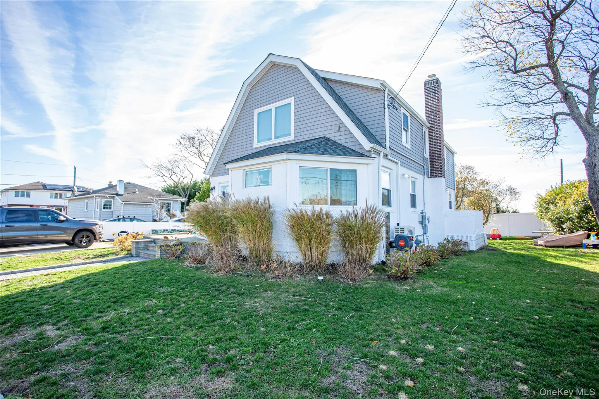 View of front of home featuring a front lawn, a chimney, a gambrel roof, and a shingled roof View of front of home featuring a front lawn, a chimney, a gambrel roof, and a shingled roof