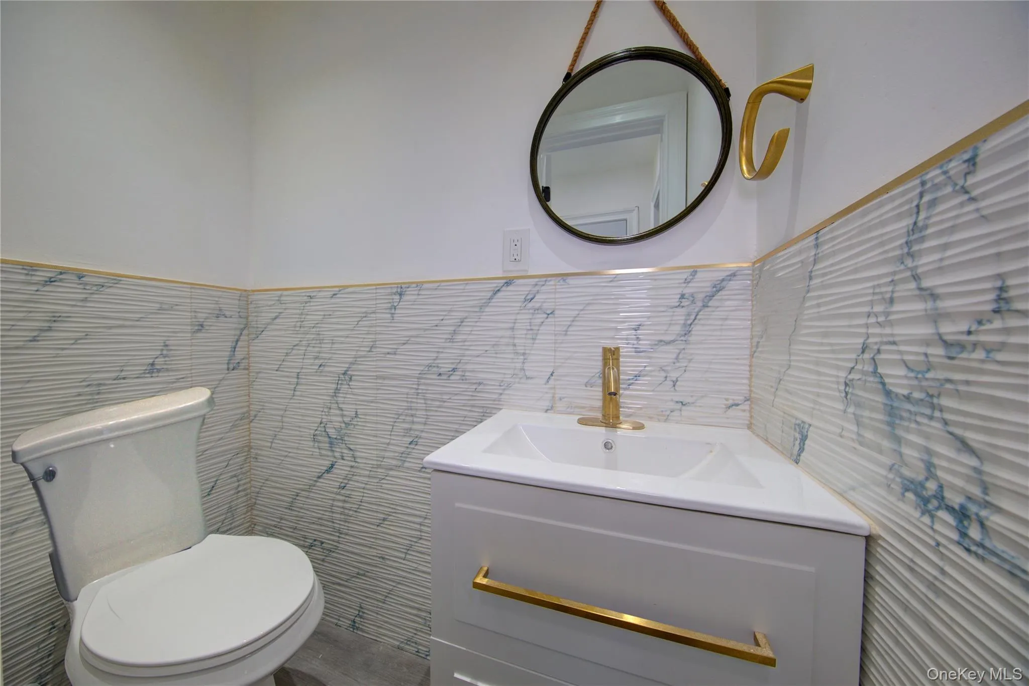 Half bathroom featuring vanity, wainscoting, and tile walls Half bathroom featuring vanity, wainscoting, and tile walls