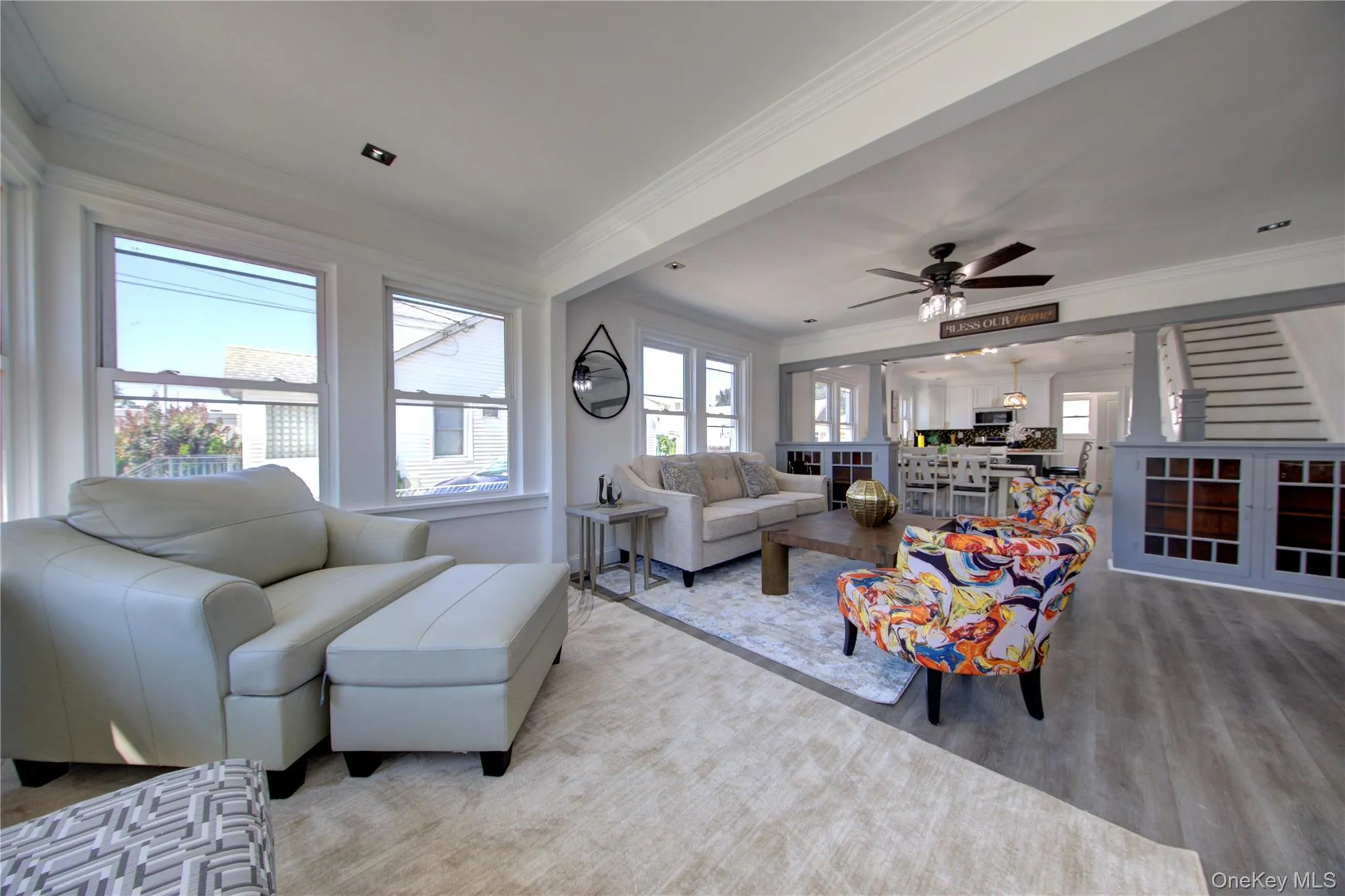 Living area with crown molding, plenty of natural light, ceiling fan, stairs, and wood finished floors Living area with crown molding, plenty of natural light, ceiling fan, stairs, and wood finished floors