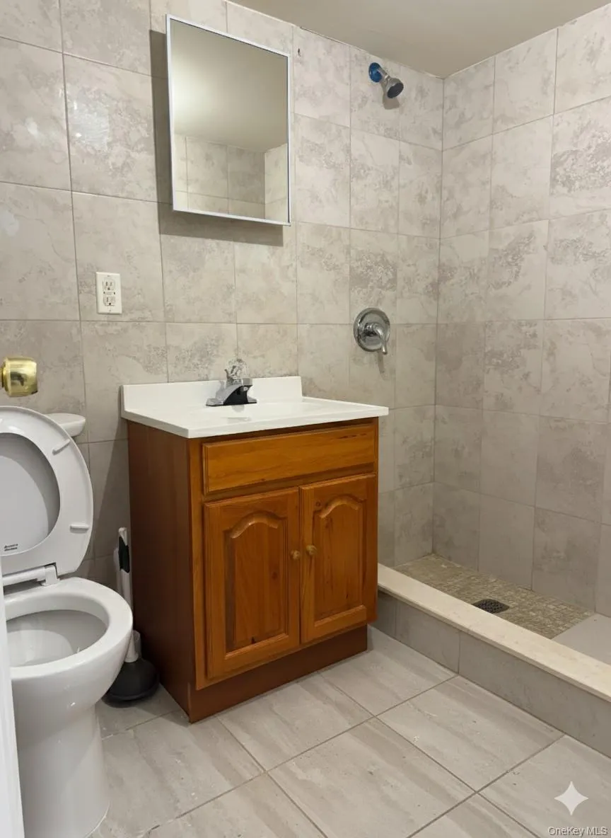 Full bathroom with a stall shower, vanity, and tile walls Full bathroom with a stall shower, vanity, and tile walls