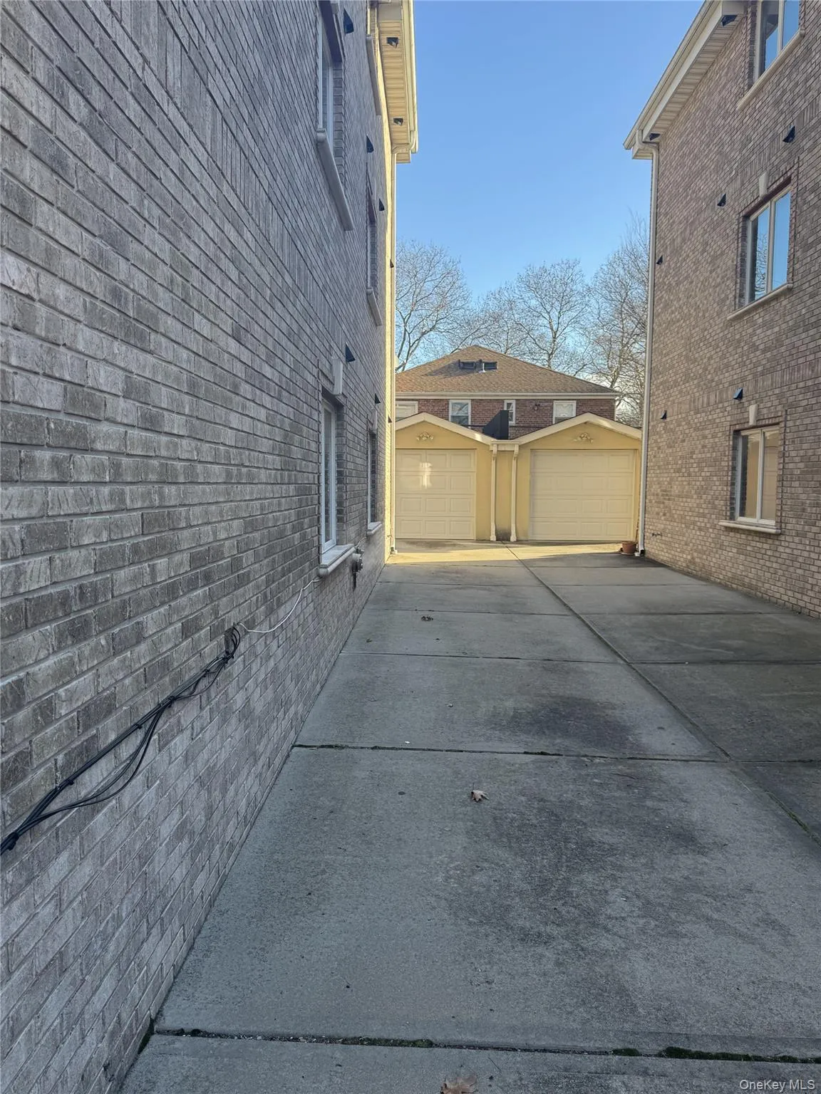View of side of home with an outdoor structure, a garage, and brick siding View of side of home with an outdoor structure, a garage, and brick siding