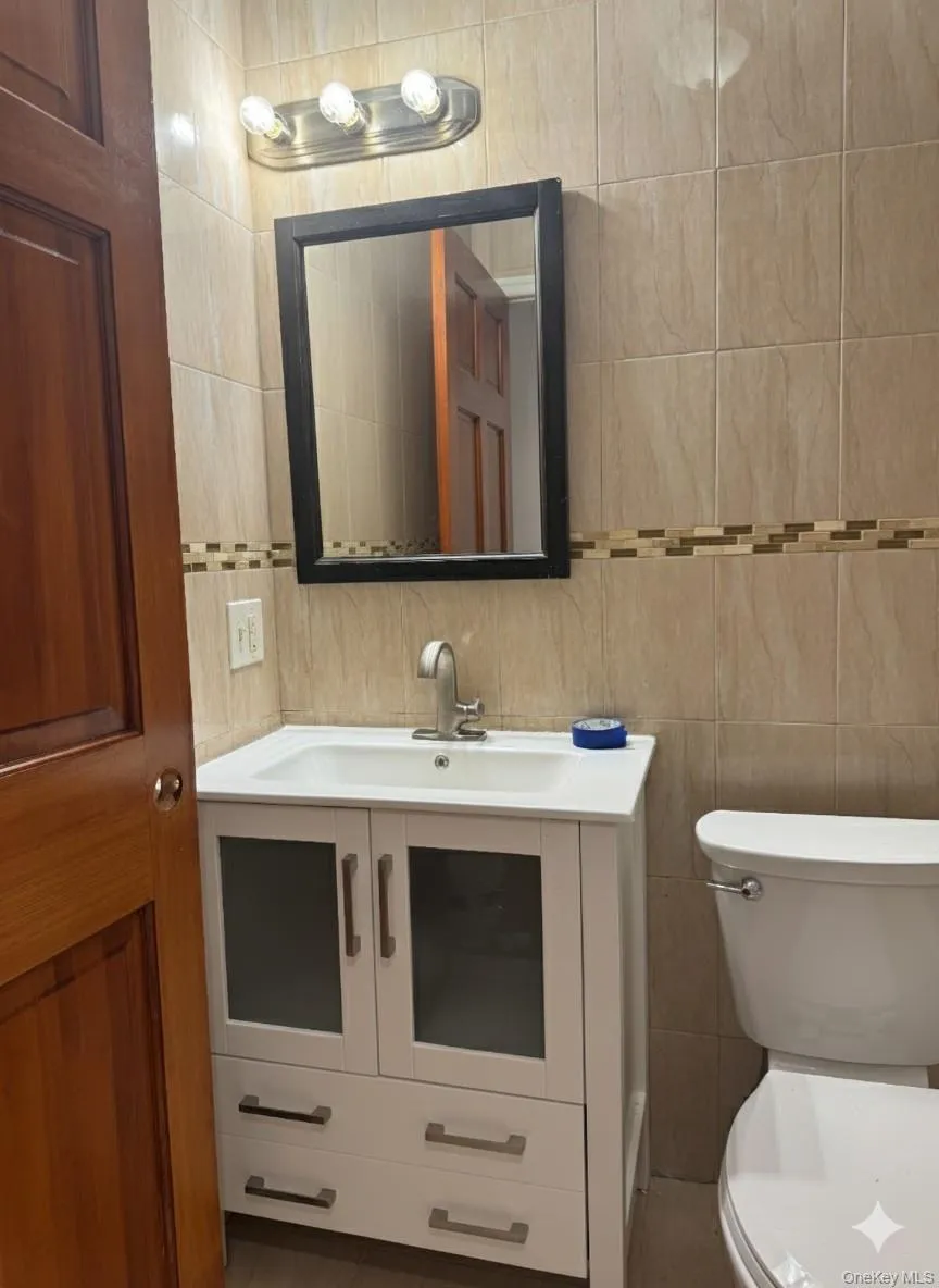 Half bathroom with tile walls and vanity Half bathroom with tile walls and vanity