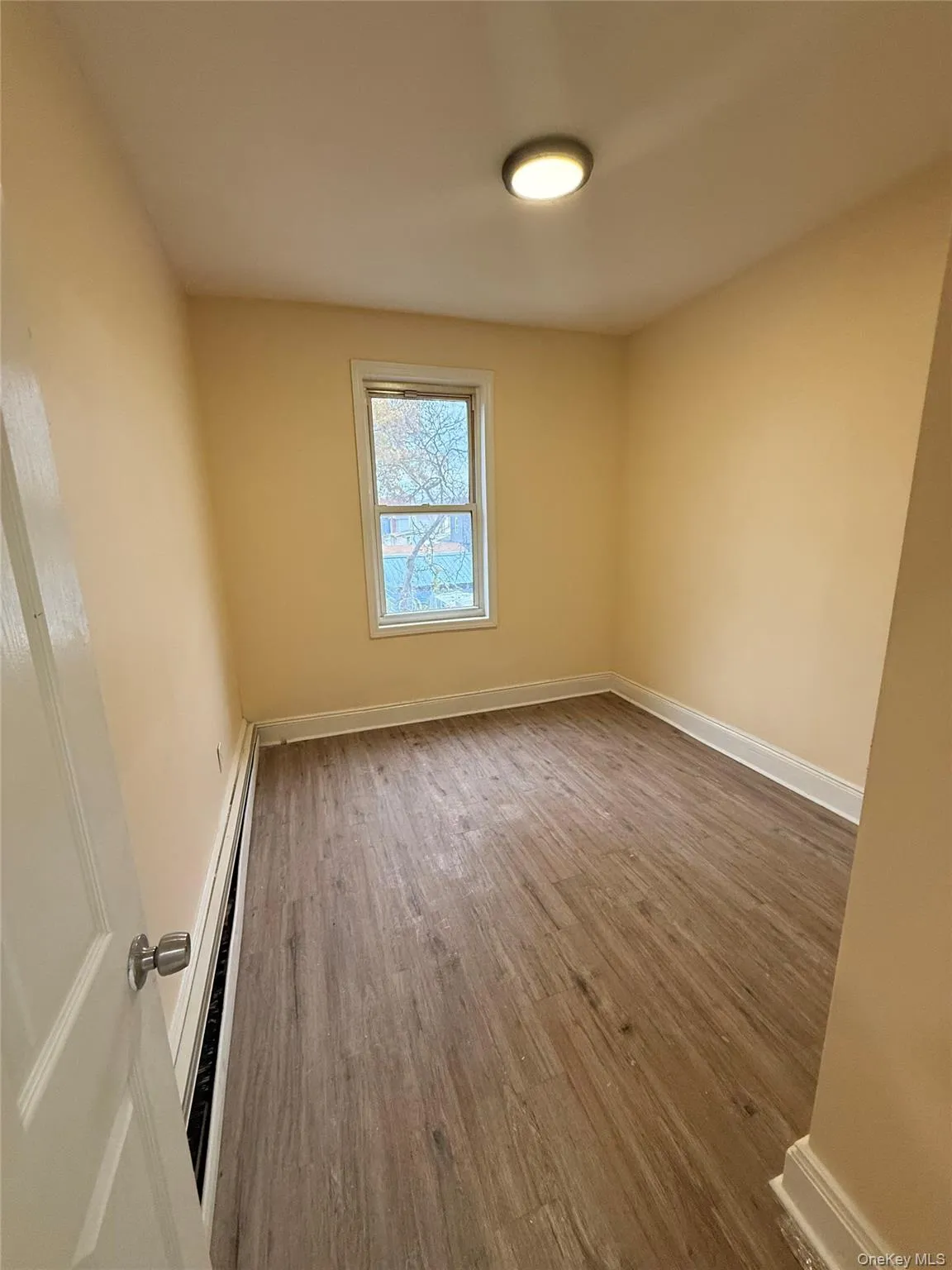 Unfurnished room with light wood-style flooring and a baseboard radiator Unfurnished room with light wood-style flooring and a baseboard radiator