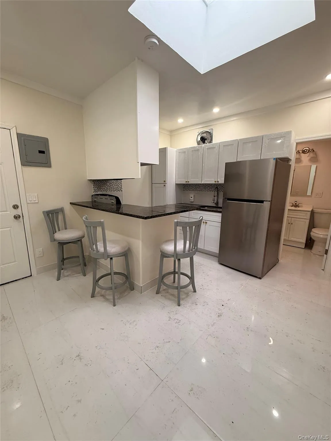 Kitchen featuring a breakfast bar, freestanding refrigerator, a peninsula, a skylight, and recessed lighting Kitchen featuring a breakfast bar, freestanding refrigerator, a peninsula, a skylight, and recessed lighting