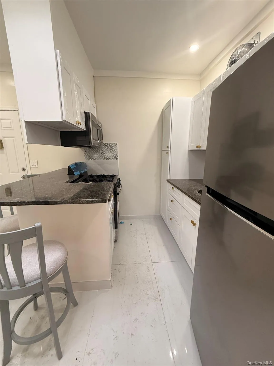 Kitchen featuring appliances with stainless steel finishes, dark stone counters, white cabinetry, a breakfast bar, and a peninsula Kitchen featuring appliances with stainless steel finishes, dark stone counters, white cabinetry, a breakfast bar, and a peninsula