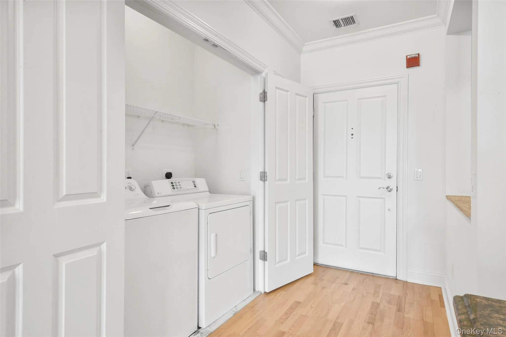 Laundry room with ornamental molding, light wood-type flooring, and washer and dryer Laundry room with ornamental molding, light wood-type flooring, and washer and dryer