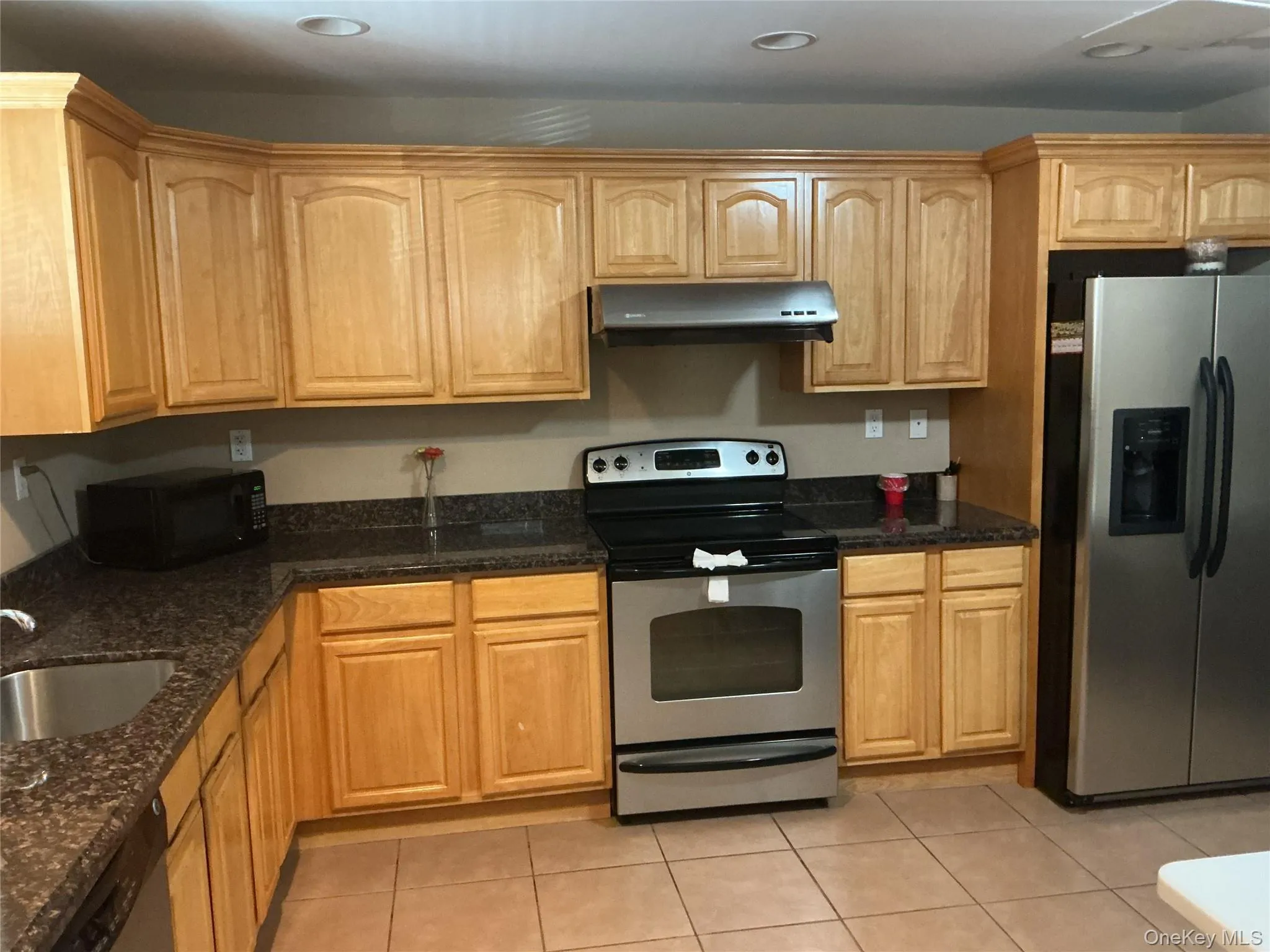 Kitchen featuring stainless steel appliances, dark stone countertops, extractor fan, light tile patterned floors, and recessed lighting Kitchen featuring stainless steel appliances, dark stone countertops, extractor fan, light tile patterned floors, and recessed lighting