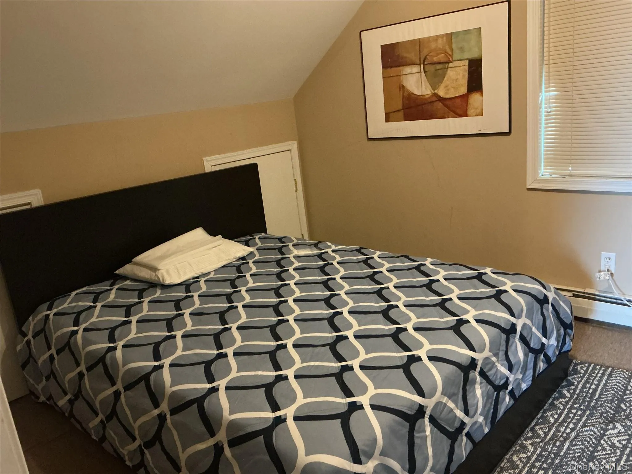 Bedroom with lofted ceiling, carpet floors, and baseboard heating Bedroom with lofted ceiling, carpet floors, and baseboard heating