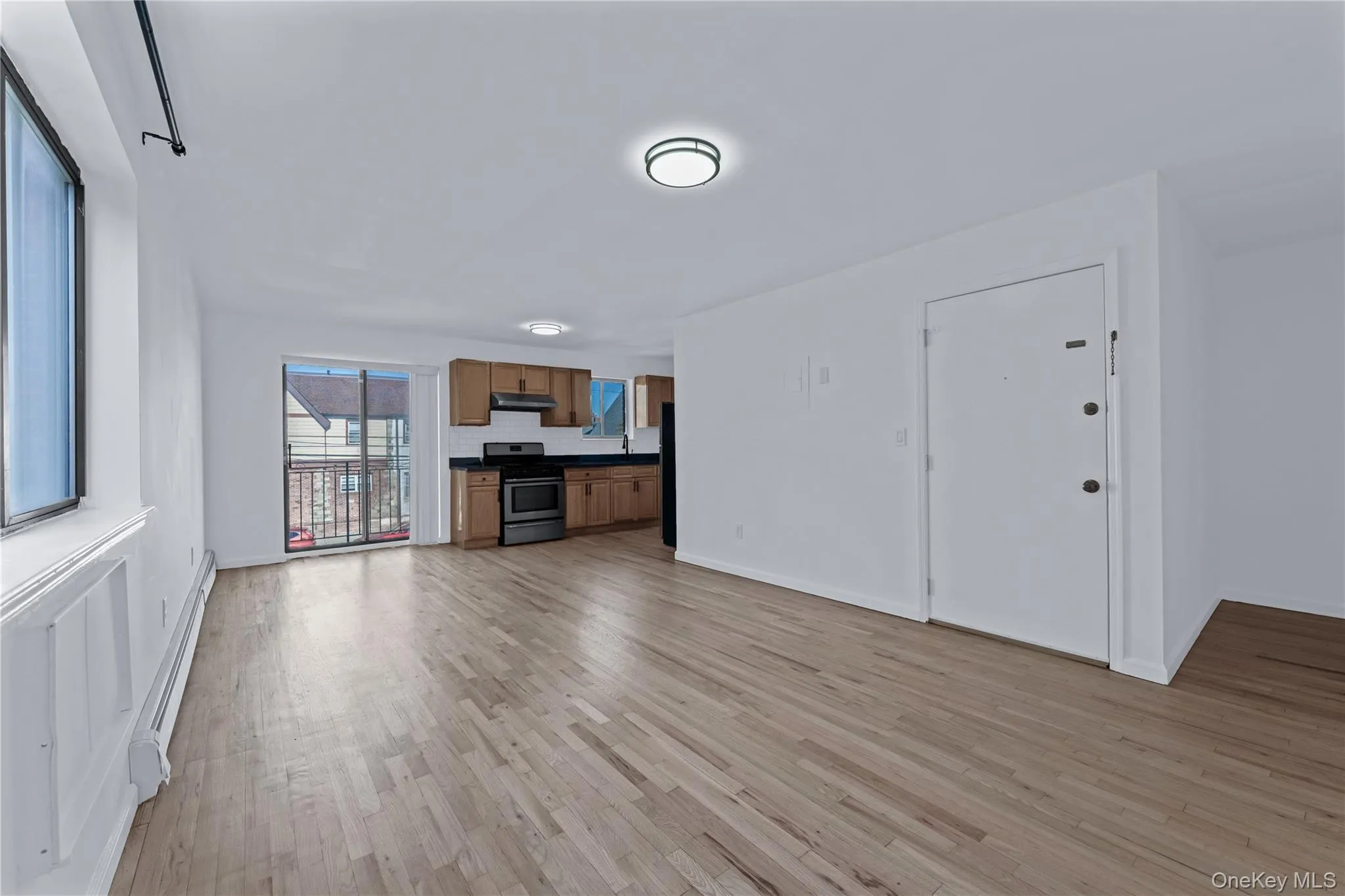Unfurnished living room with a baseboard heating unit and light wood-style floors Unfurnished living room with a baseboard heating unit and light wood-style floors