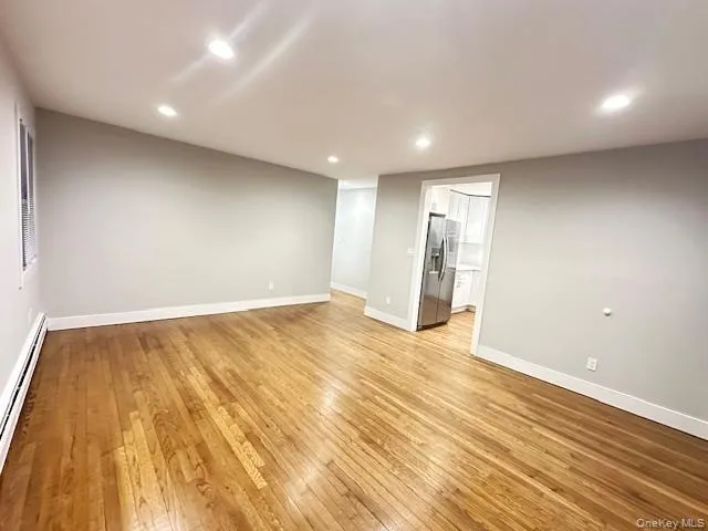 Unfurnished room featuring a baseboard radiator, recessed lighting, and light wood-style flooring Unfurnished room featuring a baseboard radiator, recessed lighting, and light wood-style flooring