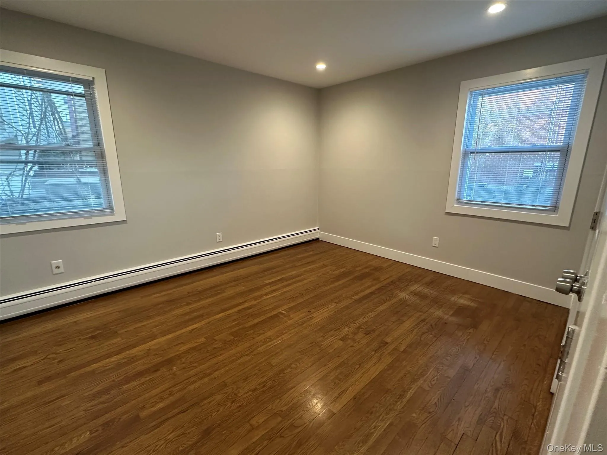 Spare room featuring baseboard heating, plenty of natural light, dark wood finished floors, and recessed lighting Spare room featuring baseboard heating, plenty of natural light, dark wood finished floors, and recessed lighting