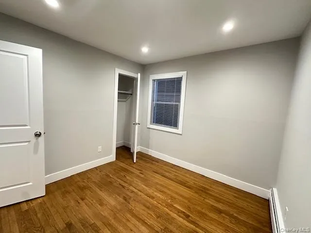 Unfurnished bedroom featuring baseboard heating, a closet, wood finished floors, and recessed lighting Unfurnished bedroom featuring baseboard heating, a closet, wood finished floors, and recessed lighting