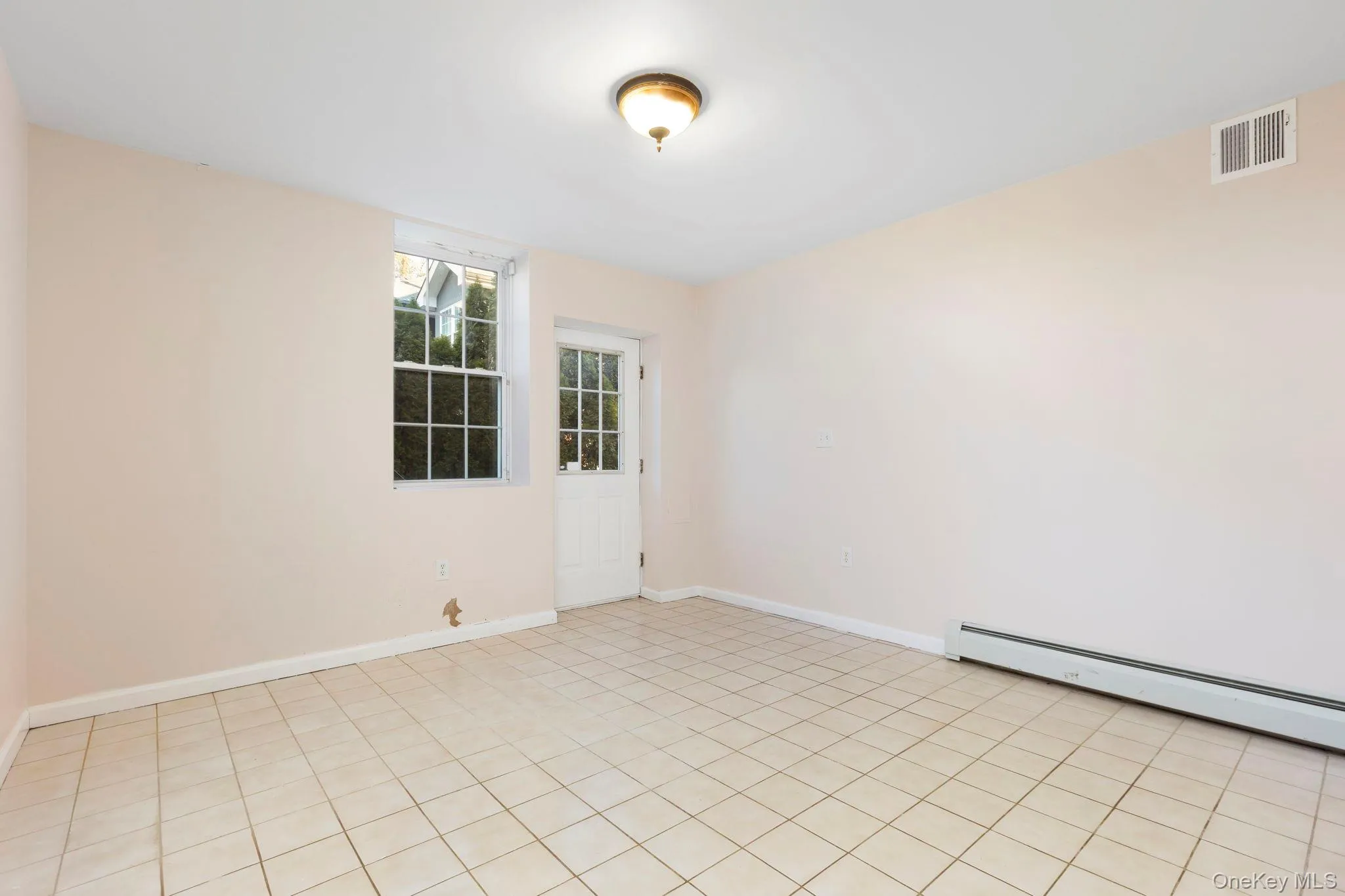 Empty room featuring a baseboard heating unit and light tile patterned floors Empty room featuring a baseboard heating unit and light tile patterned floors