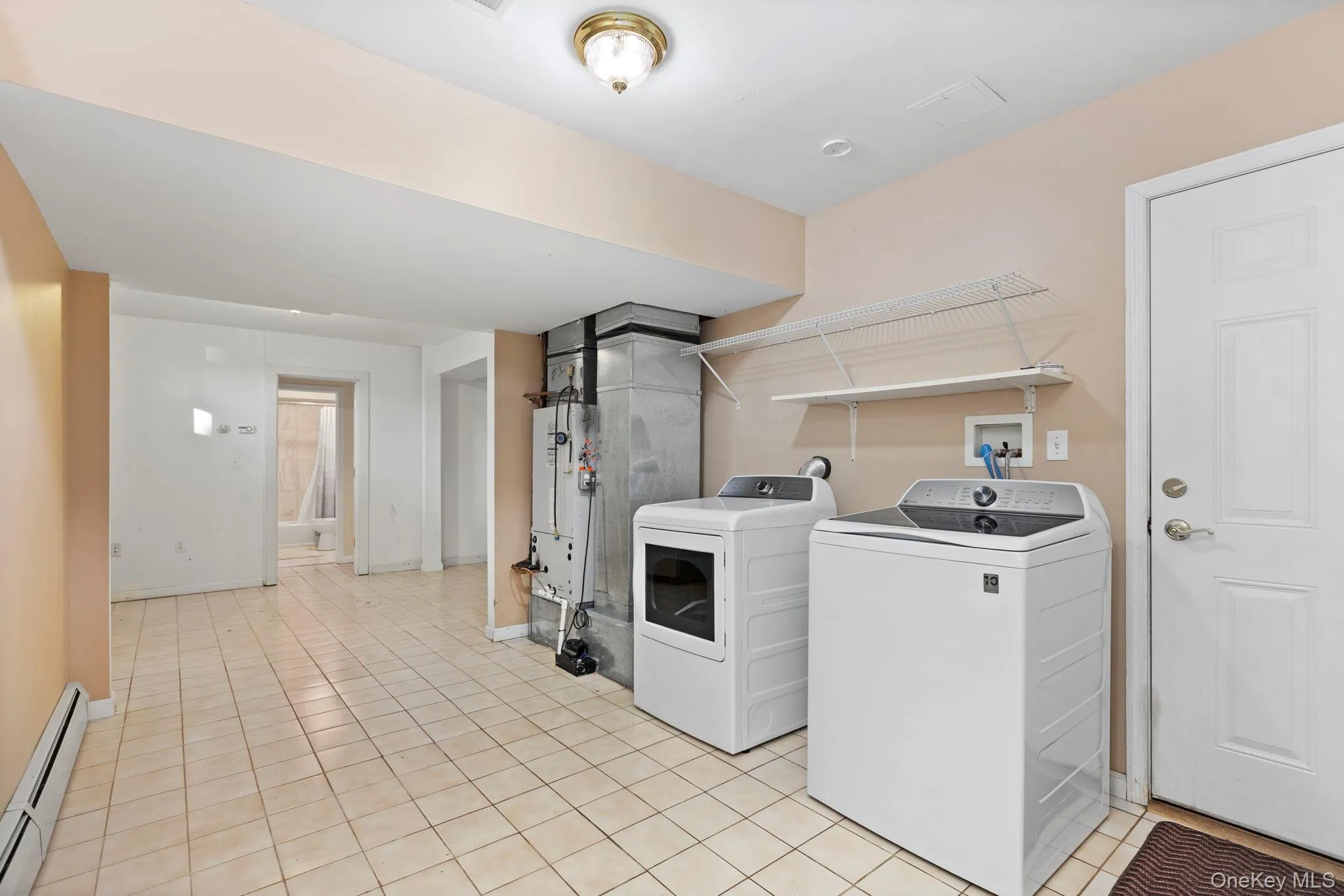Washroom with a baseboard radiator, separate washer and dryer, light tile patterned floors, and heating unit Washroom with a baseboard radiator, separate washer and dryer, light tile patterned floors, and heating unit