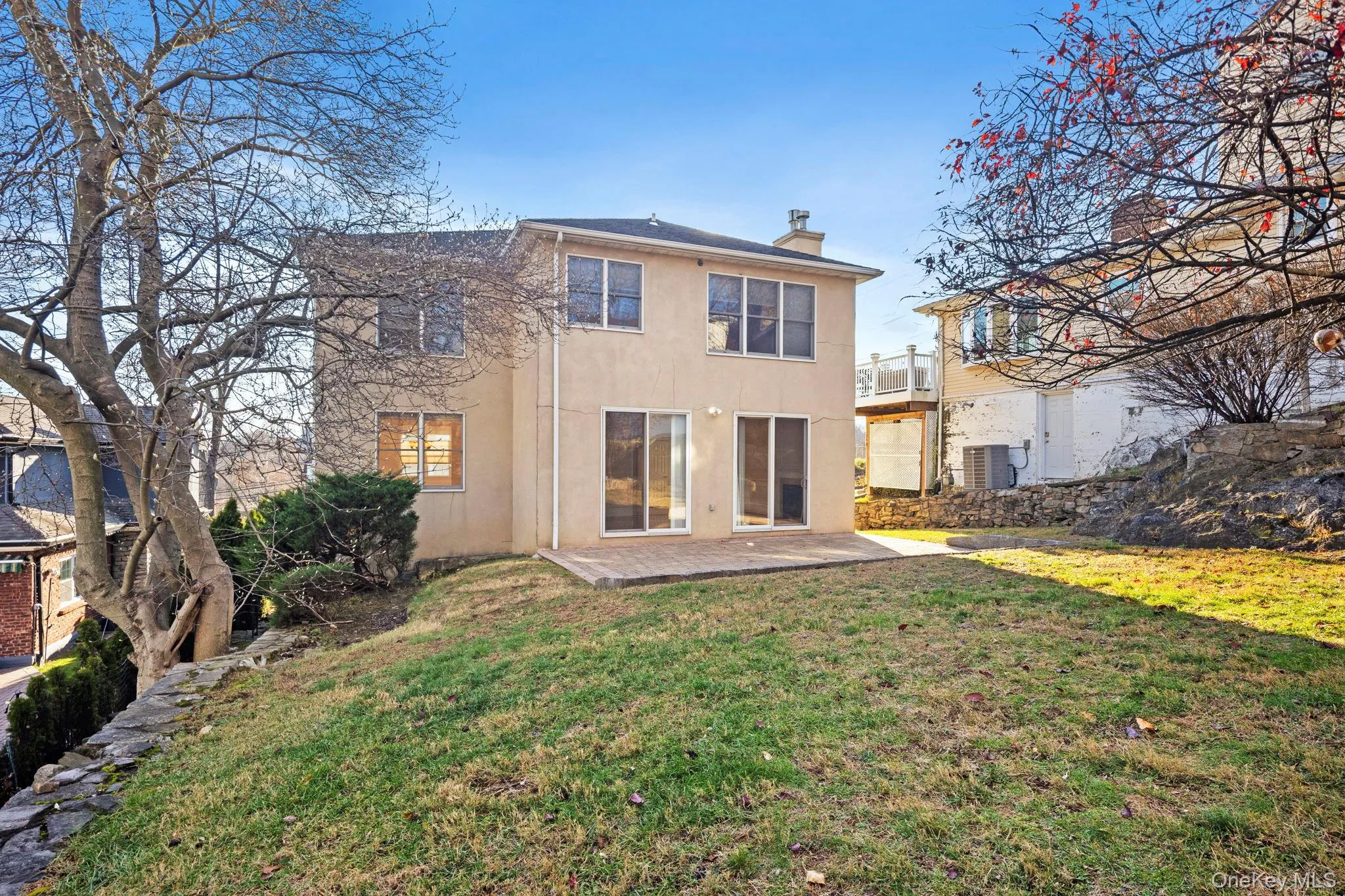 Rear view of property with a patio area, a chimney, stucco siding, a yard, and a balcony Rear view of property with a patio area, a chimney, stucco siding, a yard, and a balcony