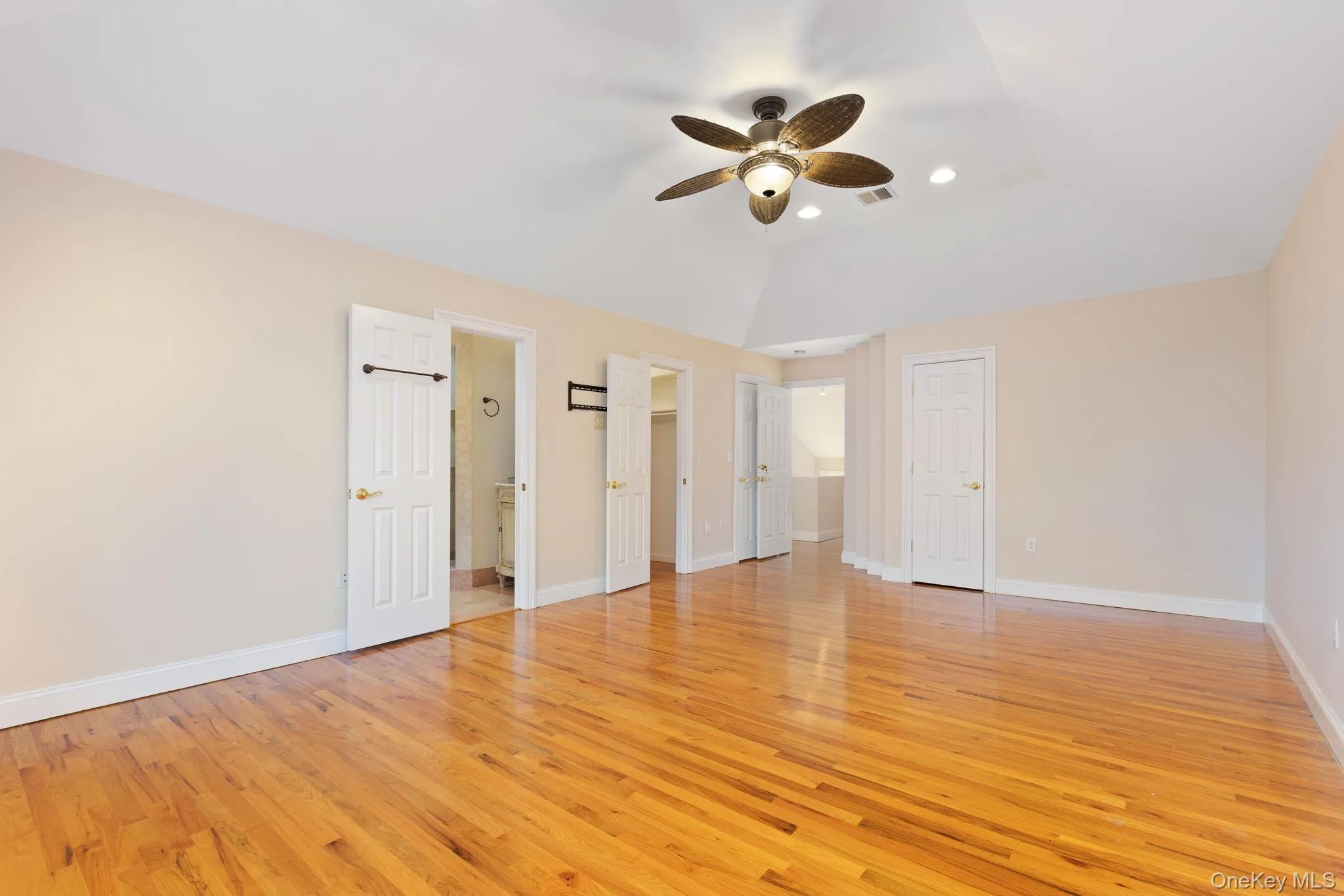 Unfurnished bedroom featuring a walk in closet, light wood-style flooring, a ceiling fan, recessed lighting, and lofted ceiling Unfurnished bedroom featuring a walk in closet, light wood-style flooring, a ceiling fan, recessed lighting, and lofted ceiling