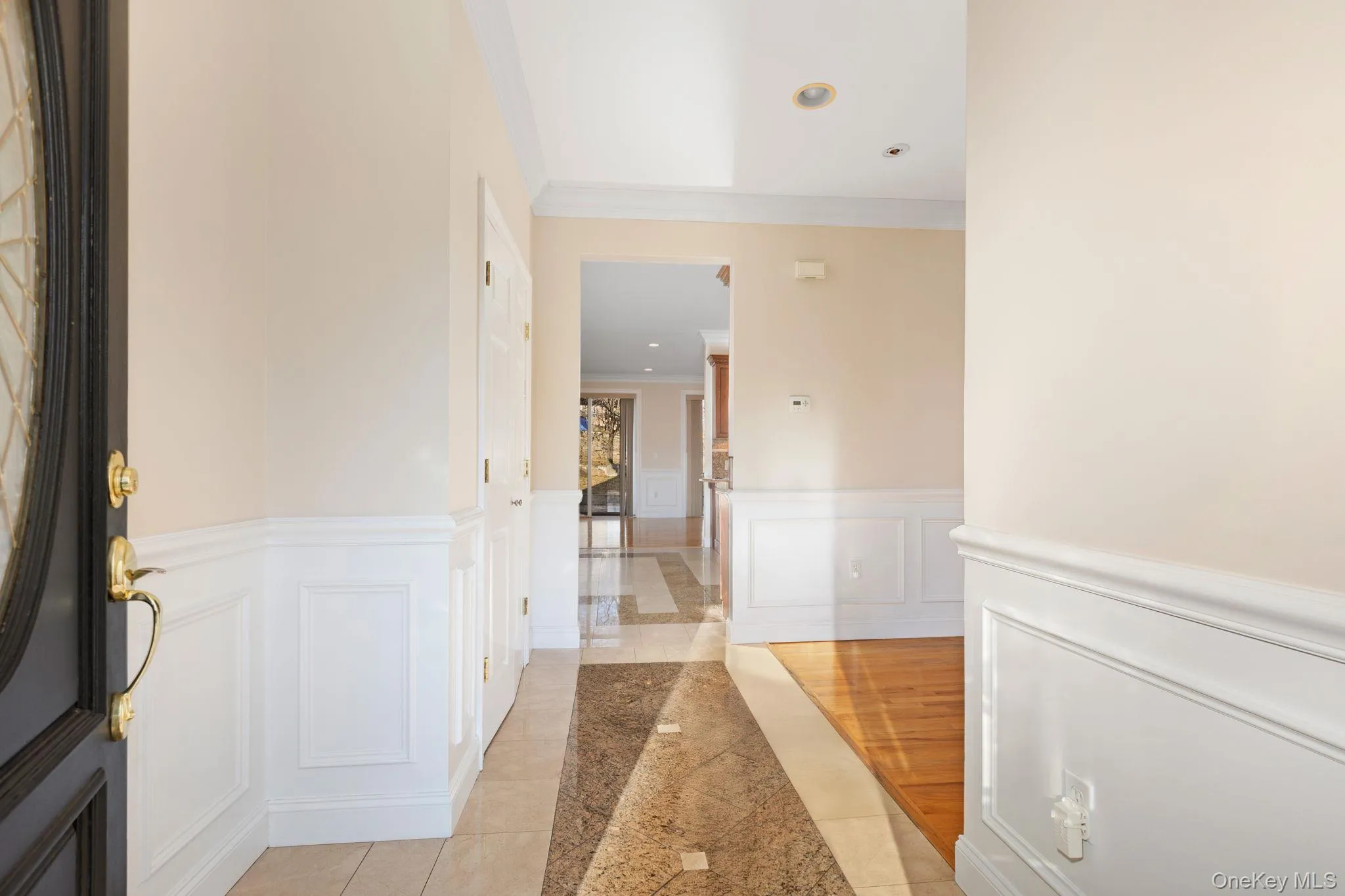 Hallway featuring crown molding, a wainscoted wall, and a decorative wall Hallway featuring crown molding, a wainscoted wall, and a decorative wall