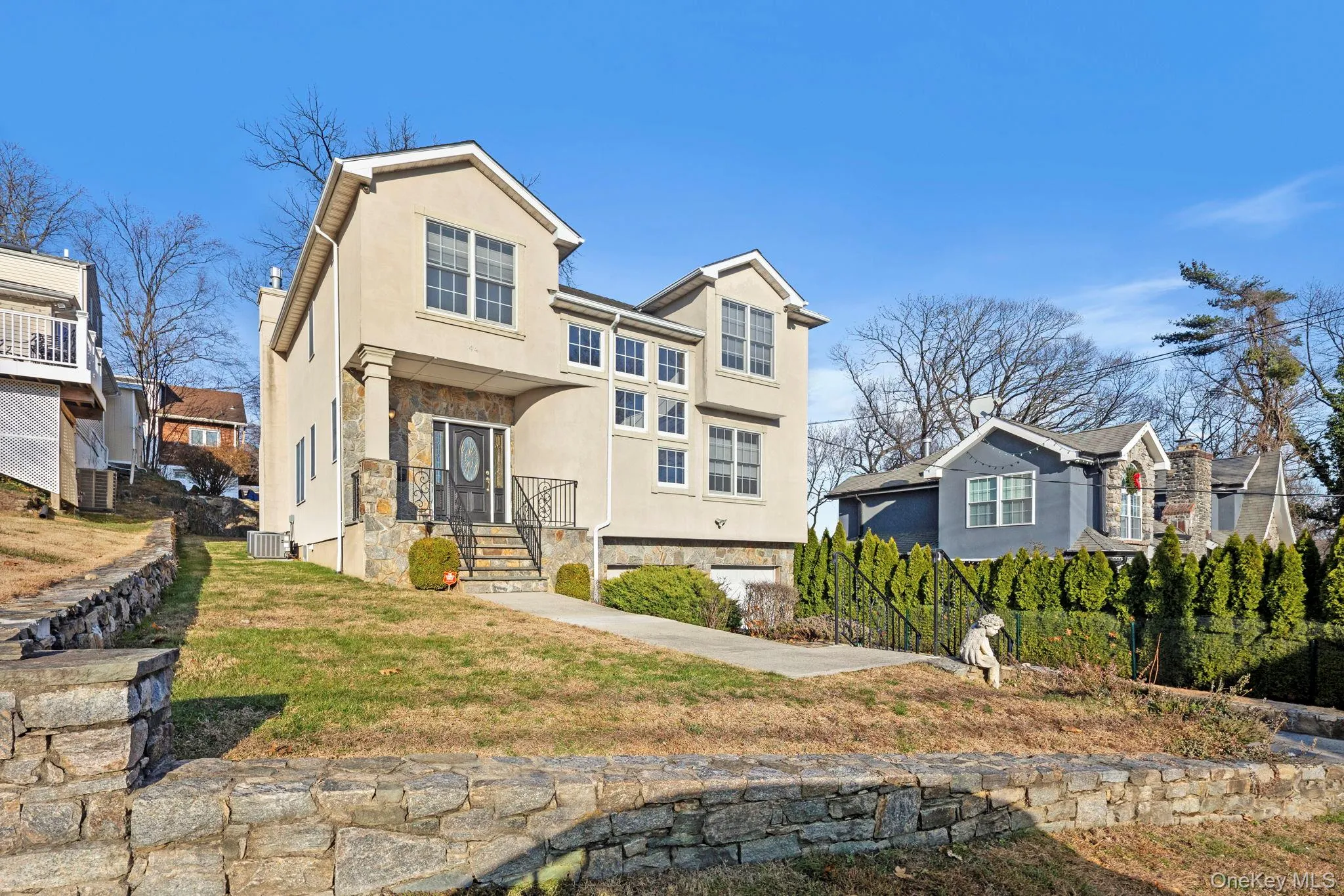 Traditional-style home with stucco siding, a front lawn, and stone siding Traditional-style home with stucco siding, a front lawn, and stone siding