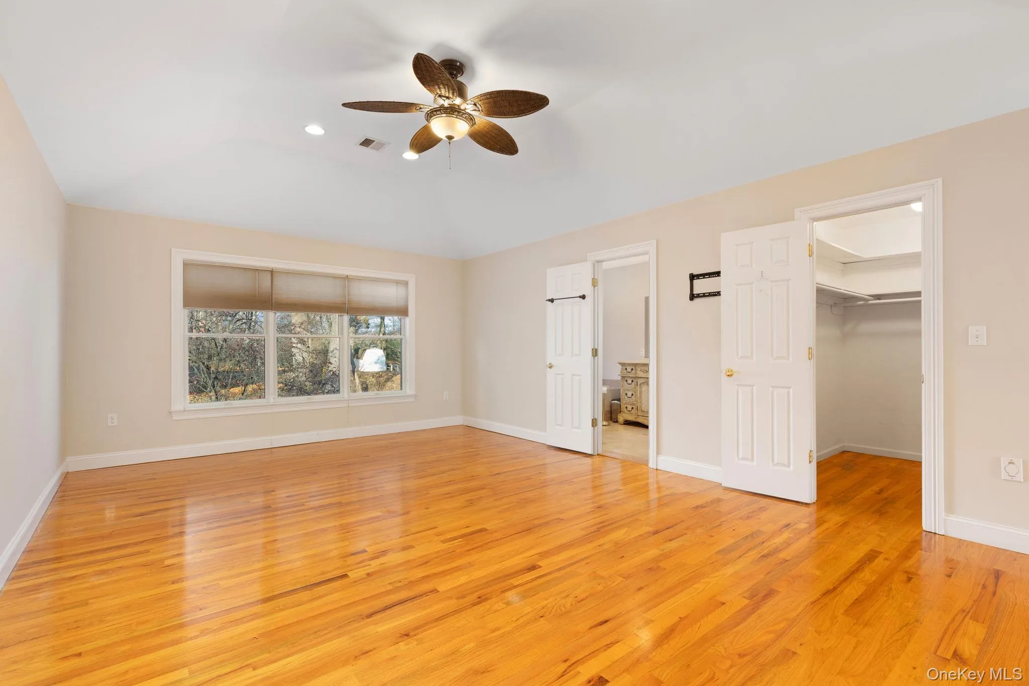 Unfurnished bedroom featuring light wood-type flooring, a spacious closet, a ceiling fan, lofted ceiling, and recessed lighting Unfurnished bedroom featuring light wood-type flooring, a spacious closet, a ceiling fan, lofted ceiling, and recessed lighting
