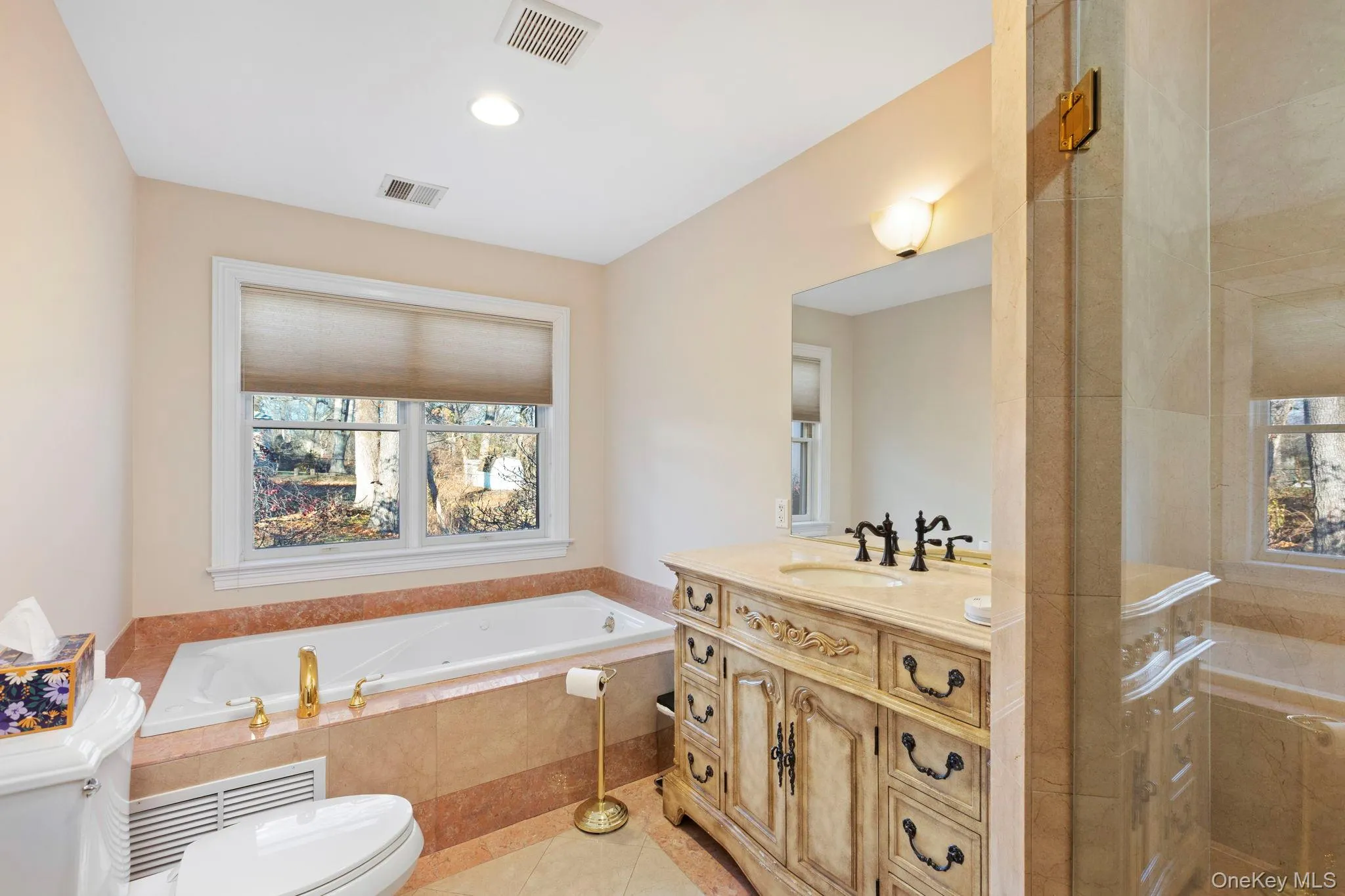 Bathroom featuring a garden tub, healthy amount of natural light, vanity, light tile patterned floors, and recessed lighting Bathroom featuring a garden tub, healthy amount of natural light, vanity, light tile patterned floors, and recessed lighting