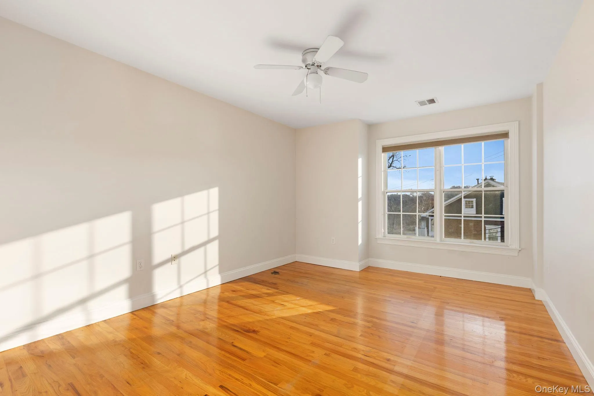 Empty room with light wood finished floors and ceiling fan Empty room with light wood finished floors and ceiling fan