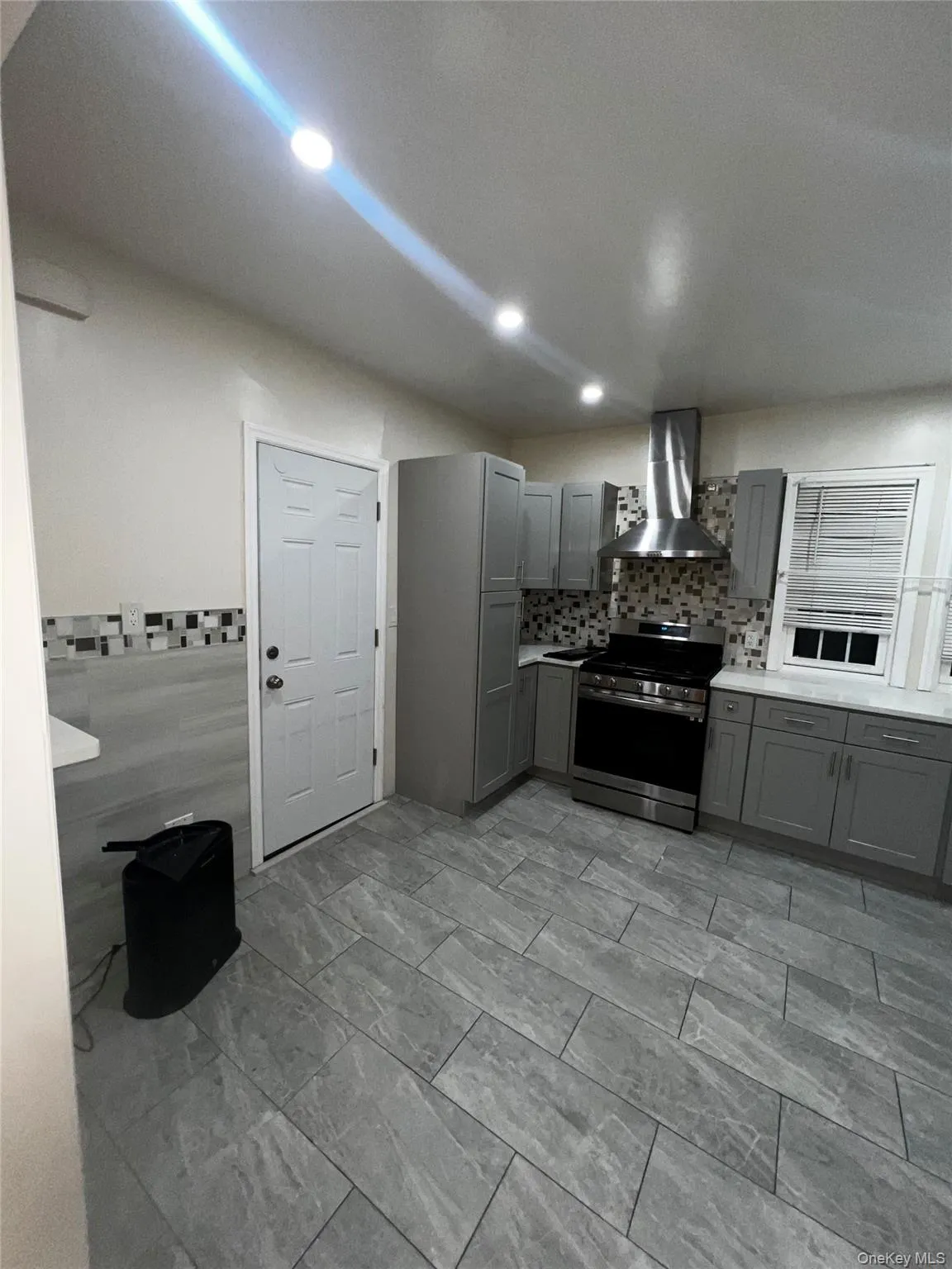 Kitchen with gray cabinetry, light countertops, electric range, wall chimney range hood, and recessed lighting Kitchen with gray cabinetry, light countertops, electric range, wall chimney range hood, and recessed lighting