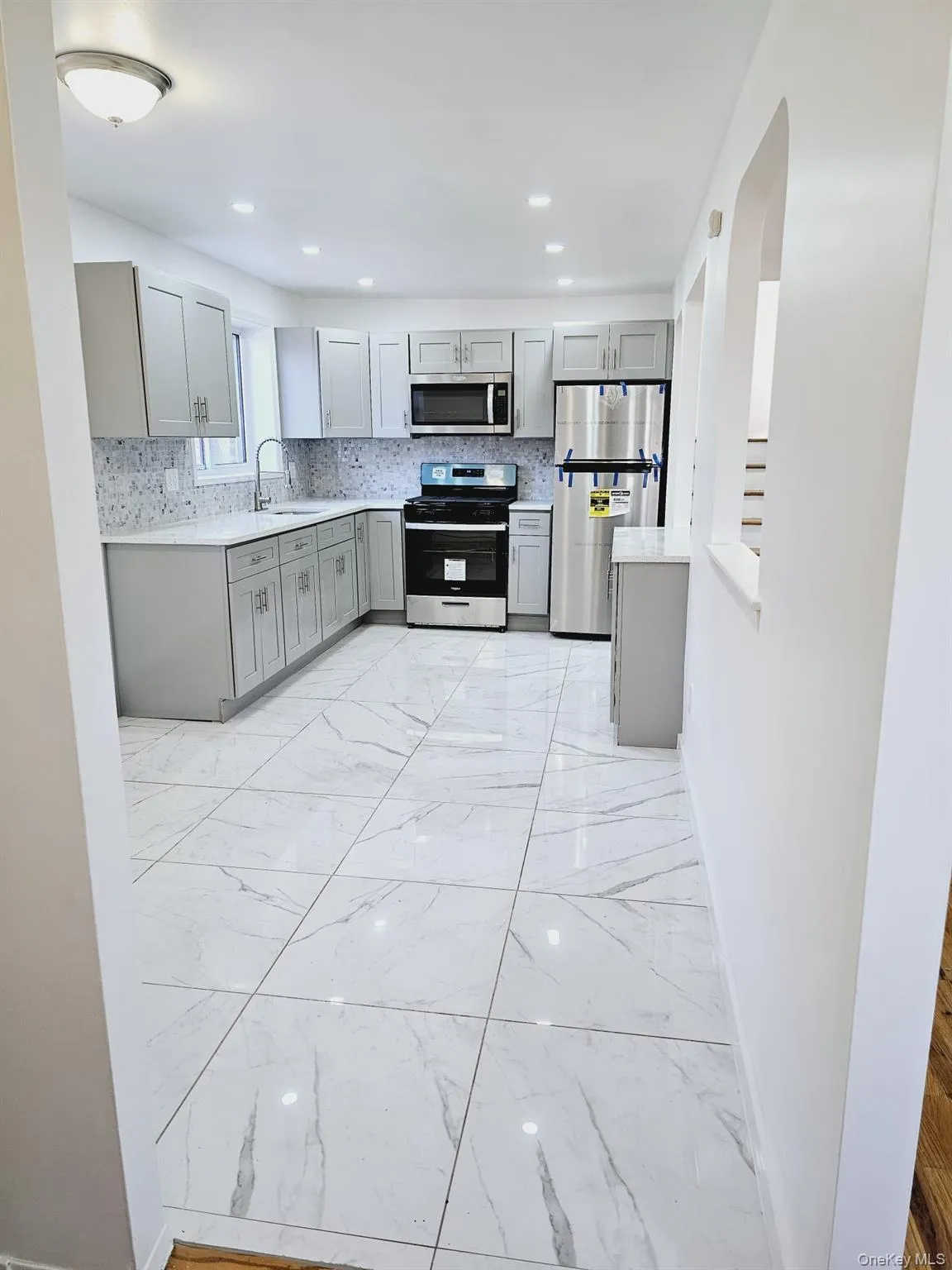 Kitchen featuring gray cabinetry, appliances with stainless steel finishes, light stone counters, and recessed lighting Kitchen featuring gray cabinetry, appliances with stainless steel finishes, light stone counters, and recessed lighting