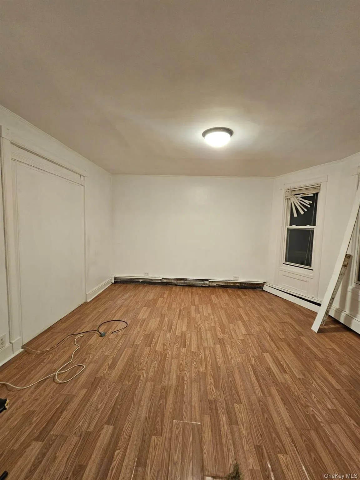 Below grade area featuring light wood finished floors and a baseboard radiator Below grade area featuring light wood finished floors and a baseboard radiator