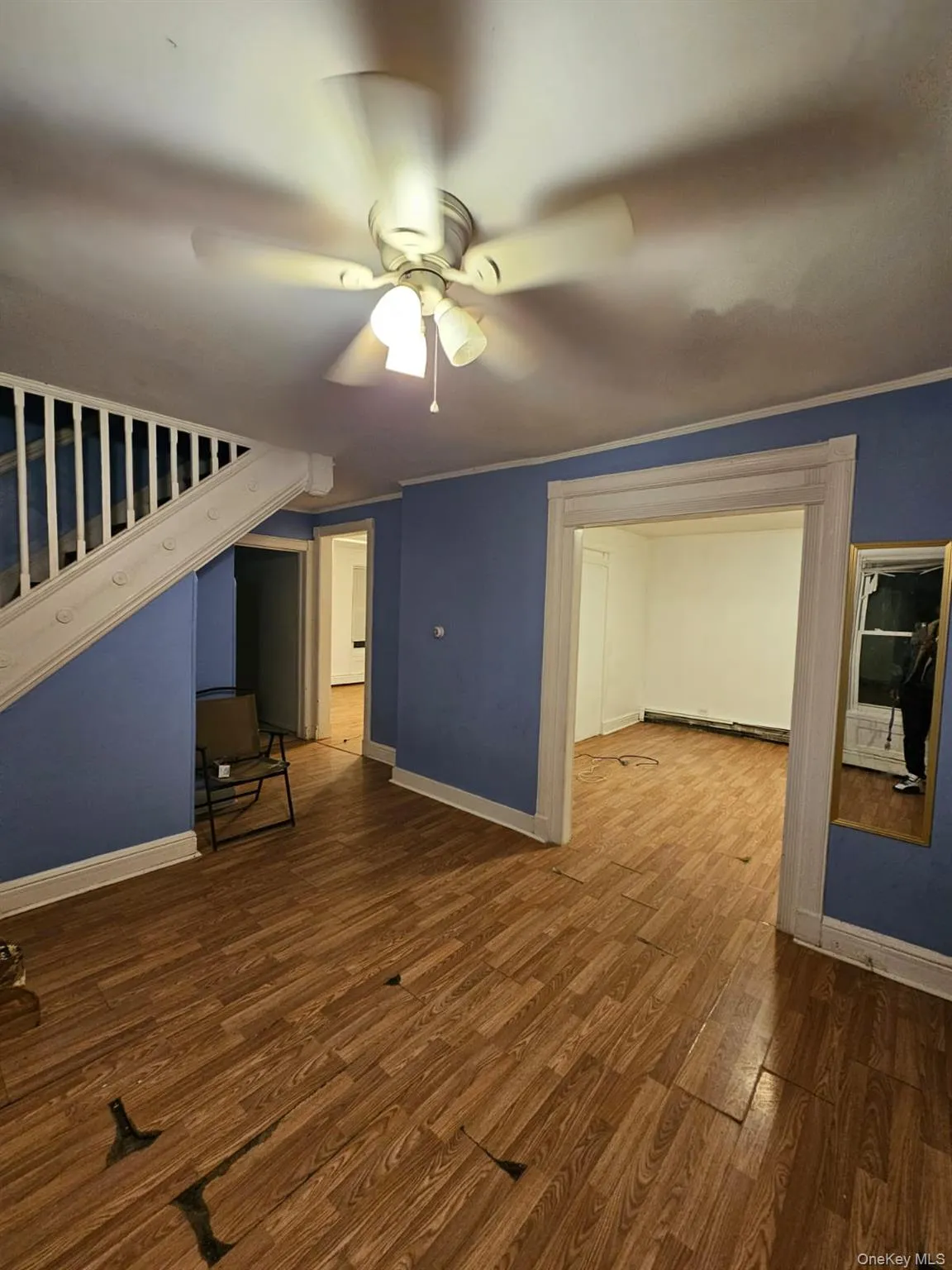 Unfurnished room featuring dark wood-style floors, ceiling fan, and stairway Unfurnished room featuring dark wood-style floors, ceiling fan, and stairway