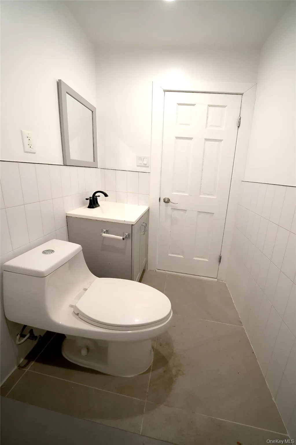 Half bathroom with tile walls, tile patterned flooring, a wainscoted wall, and vanity Half bathroom with tile walls, tile patterned flooring, a wainscoted wall, and vanity