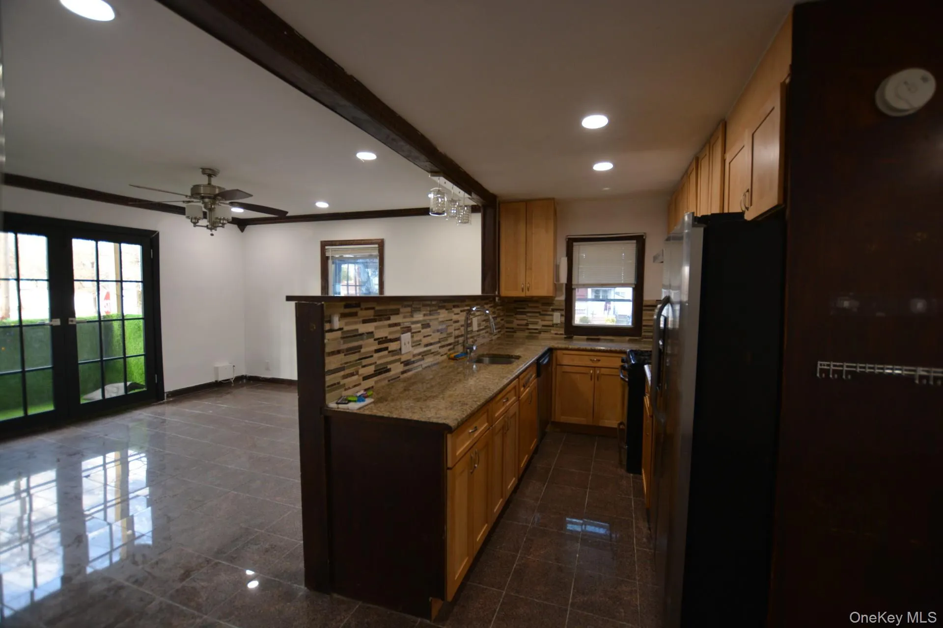 Kitchen with freestanding refrigerator, recessed lighting, plenty of natural light, dark stone countertops, and a peninsula Kitchen with freestanding refrigerator, recessed lighting, plenty of natural light, dark stone countertops, and a peninsula