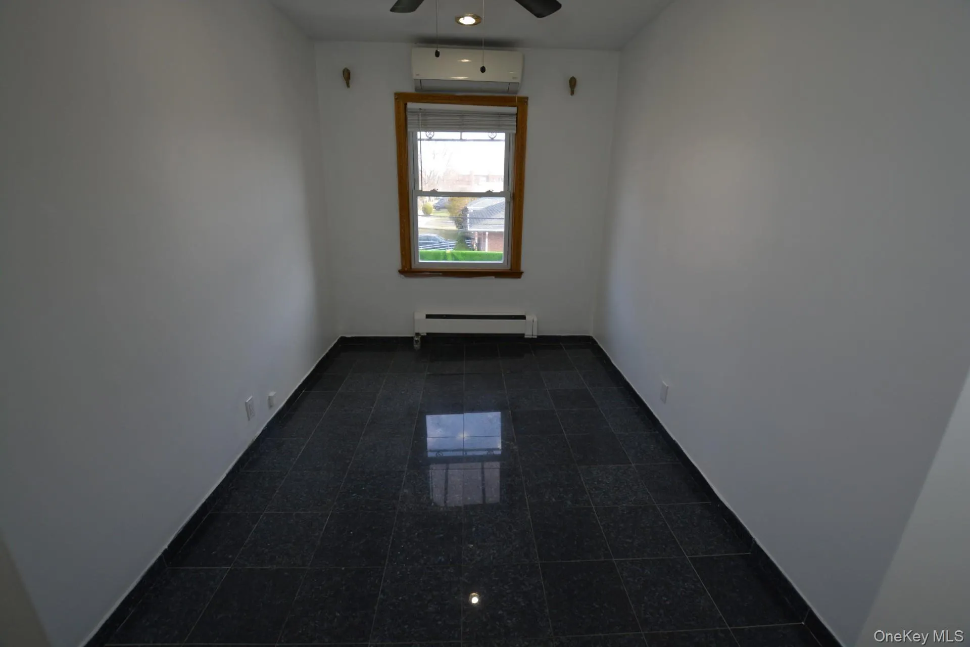 Unfurnished room with a baseboard radiator, an AC wall unit, and a ceiling fan Unfurnished room with a baseboard radiator, an AC wall unit, and a ceiling fan