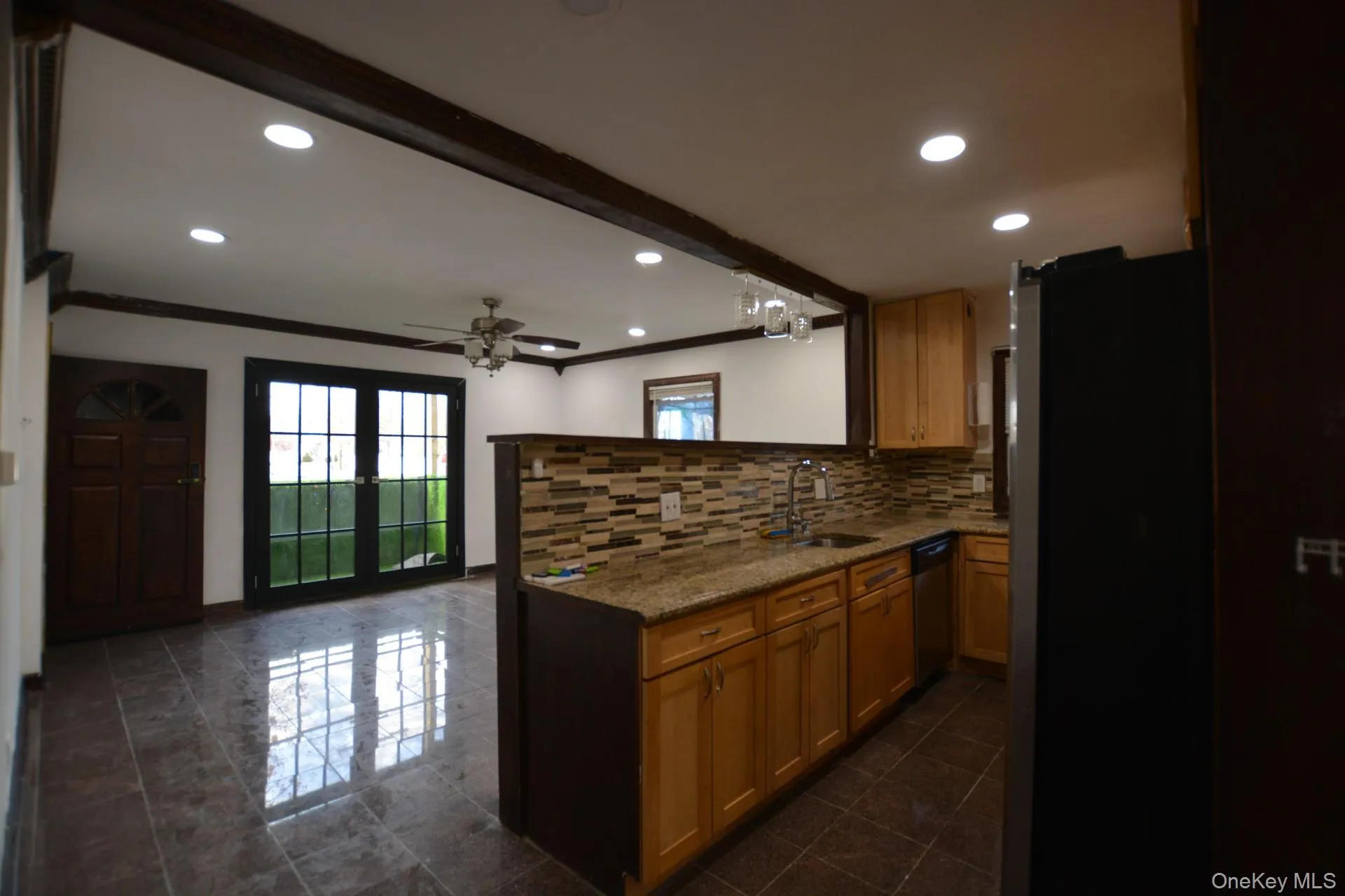 Kitchen with ornamental molding, tasteful backsplash, appliances with stainless steel finishes, a peninsula, and dark stone counters Kitchen with ornamental molding, tasteful backsplash, appliances with stainless steel finishes, a peninsula, and dark stone counters