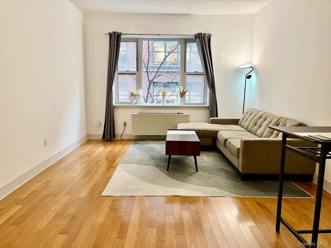 Living area with light wood-style floors and radiator heating unit Living area with light wood-style floors and radiator heating unit