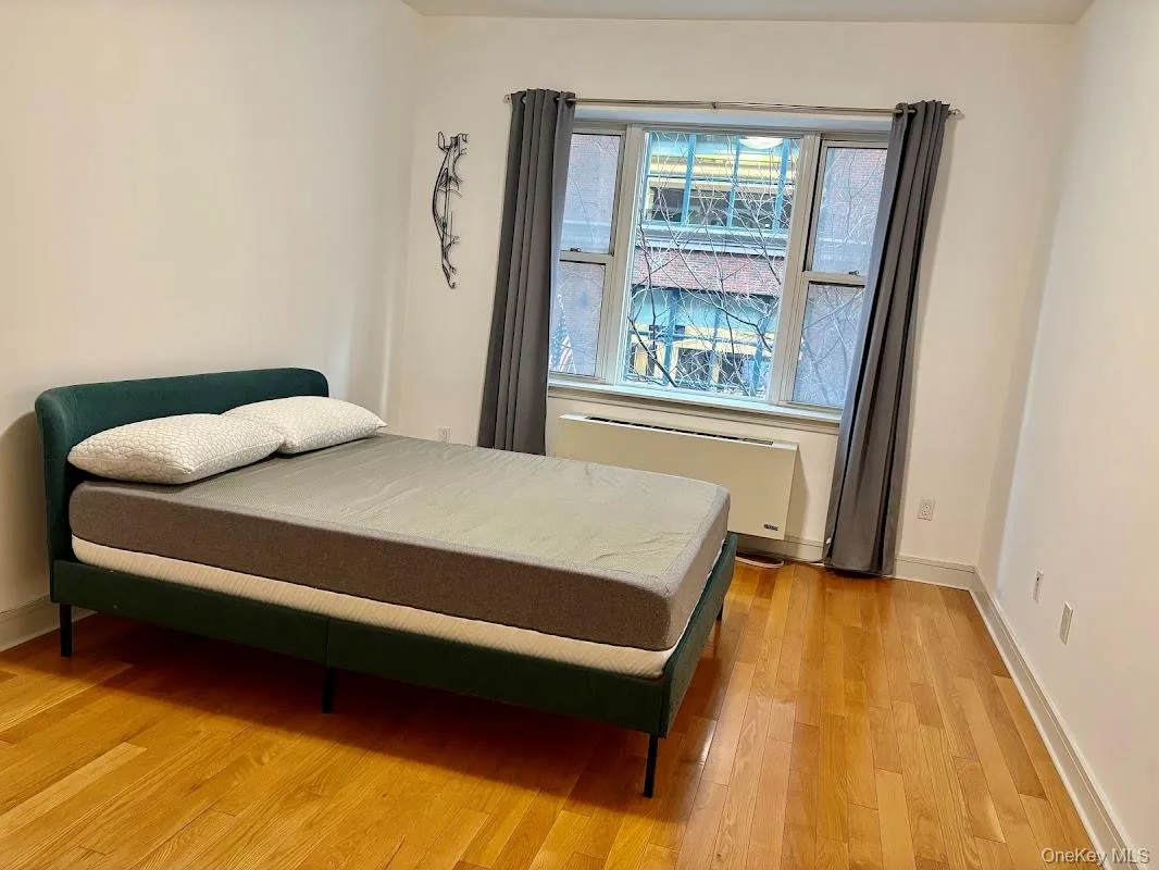 Bedroom with radiator heating unit and light wood finished floors Bedroom with radiator heating unit and light wood finished floors