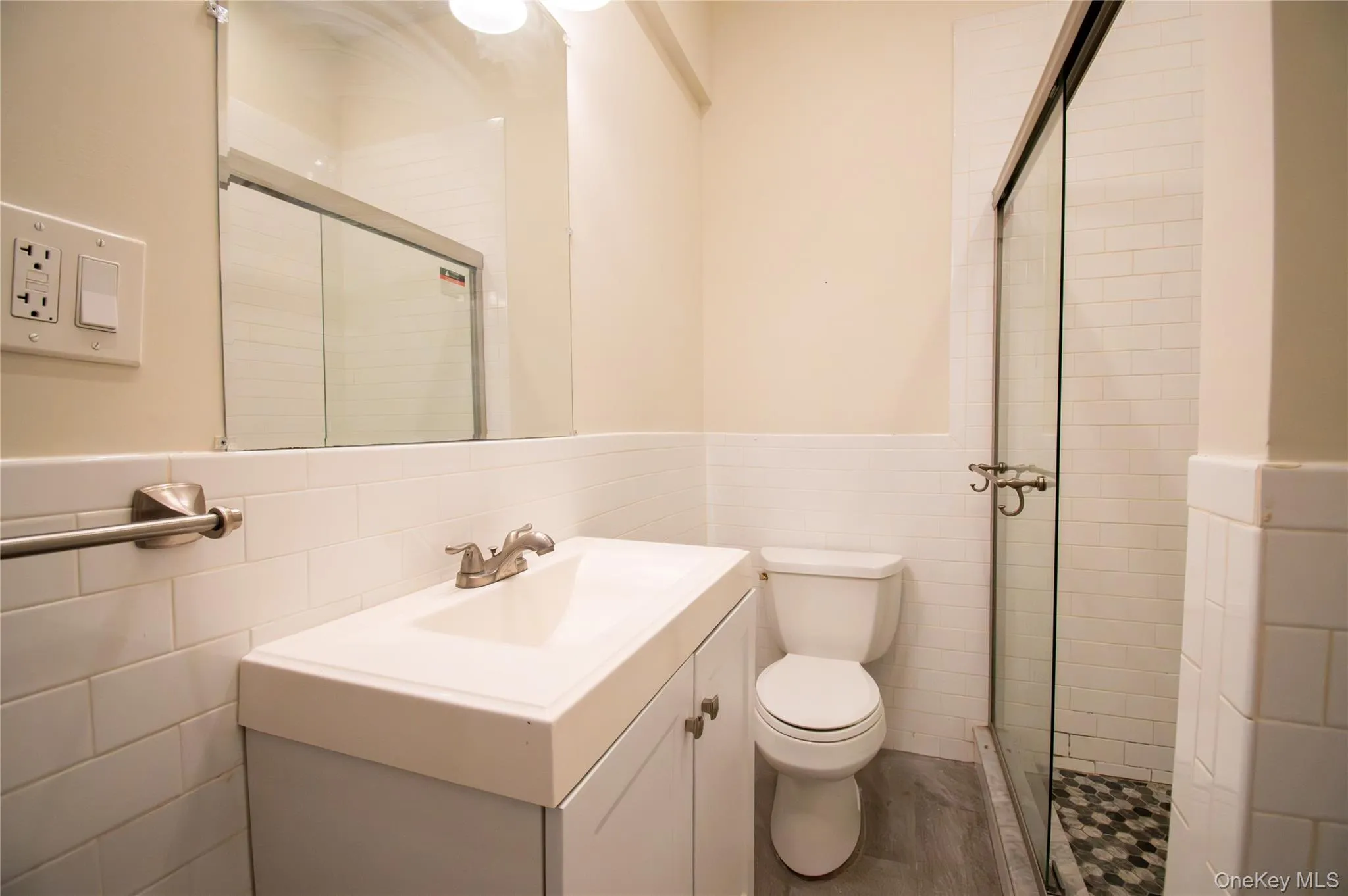 Bathroom with a wainscoted wall, a stall shower, tile walls, and vanity Bathroom with a wainscoted wall, a stall shower, tile walls, and vanity