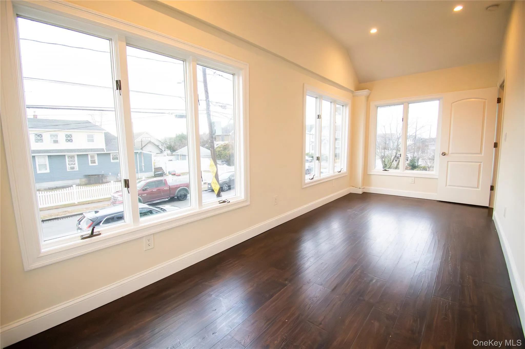 Unfurnished room with vaulted ceiling, dark wood-style floors, and recessed lighting Unfurnished room with vaulted ceiling, dark wood-style floors, and recessed lighting