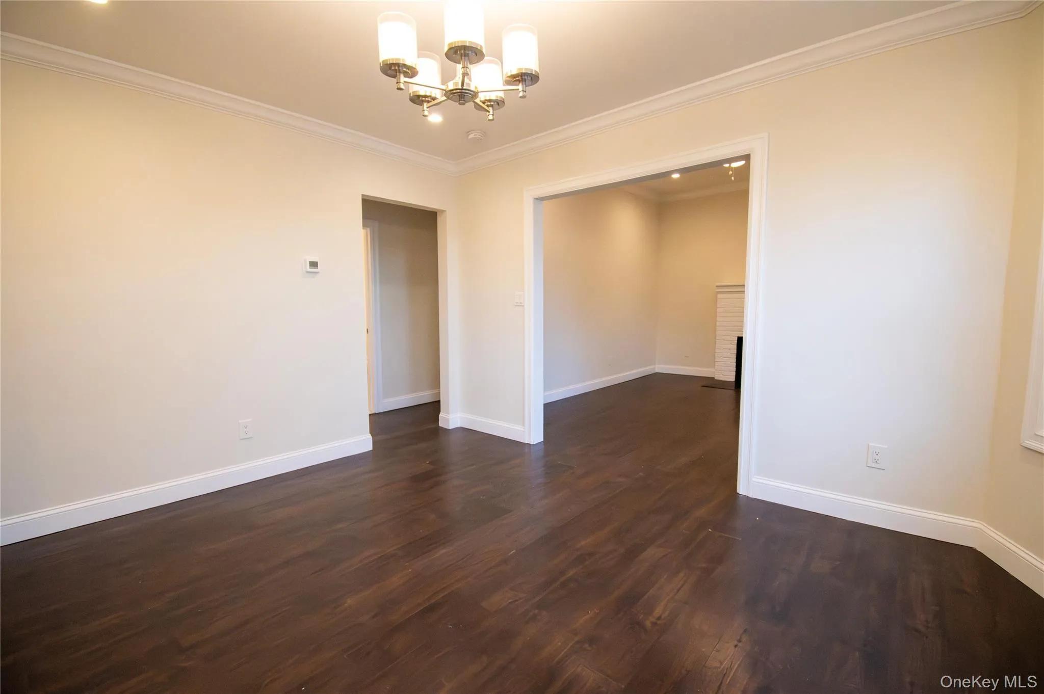 Unfurnished room with a chandelier, dark wood-style flooring, and crown molding Unfurnished room with a chandelier, dark wood-style flooring, and crown molding
