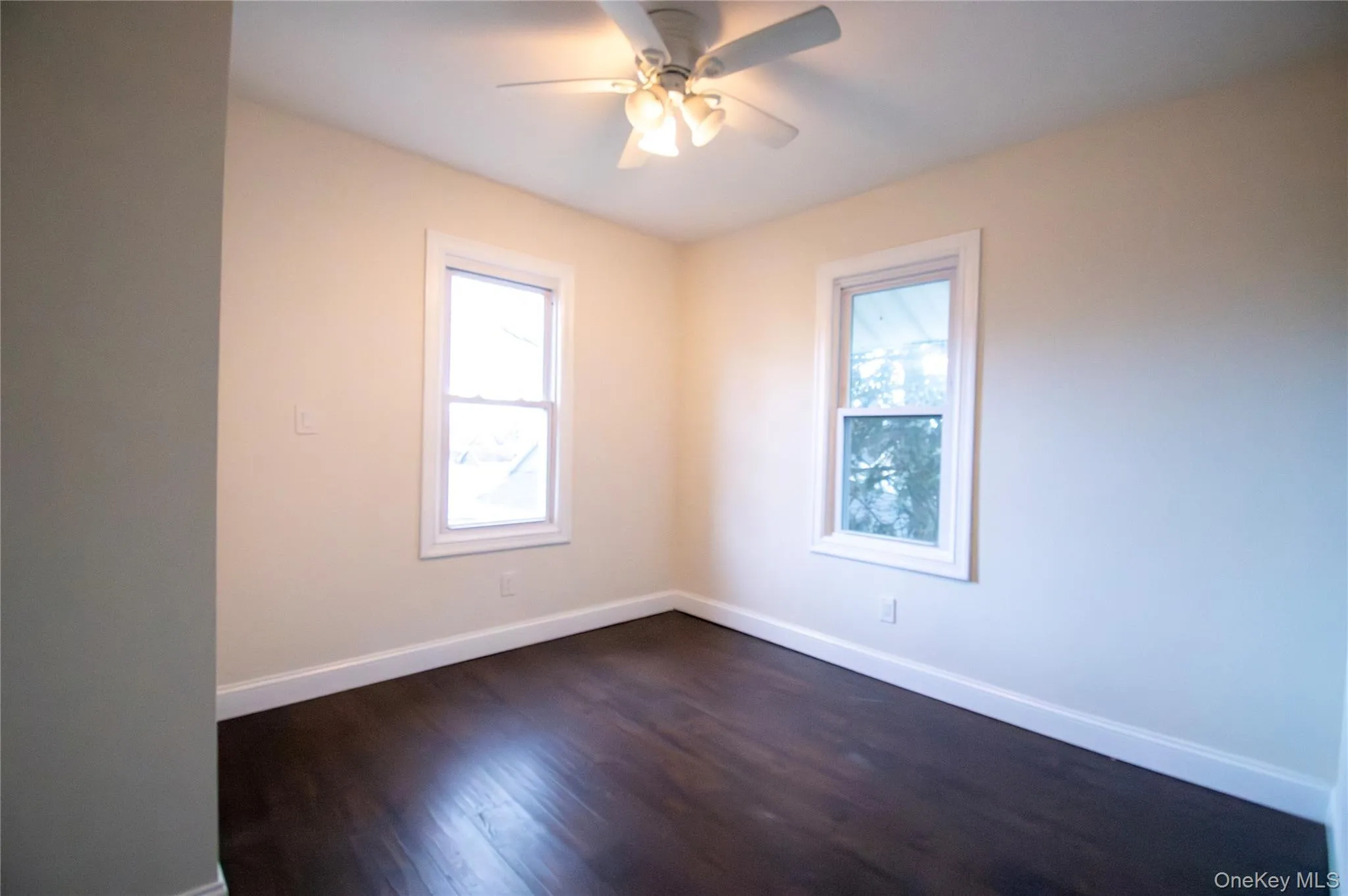 Spare room featuring dark wood-style flooring and a ceiling fan Spare room featuring dark wood-style flooring and a ceiling fan